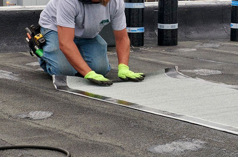 Un homme est agenouillé sur le sol et travaille sur un toit.