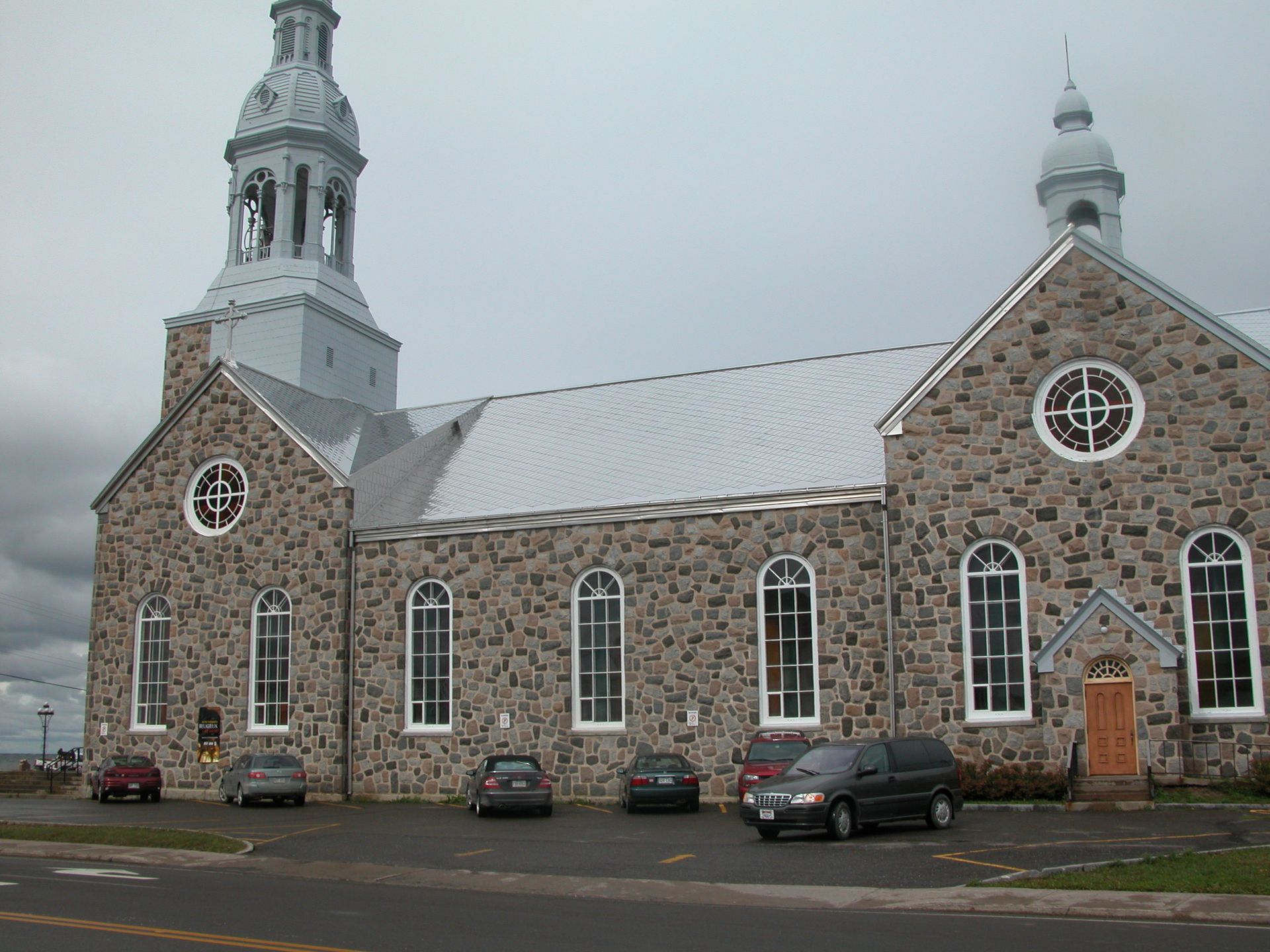 Une église avec des voitures garées devant elle par temps nuageux