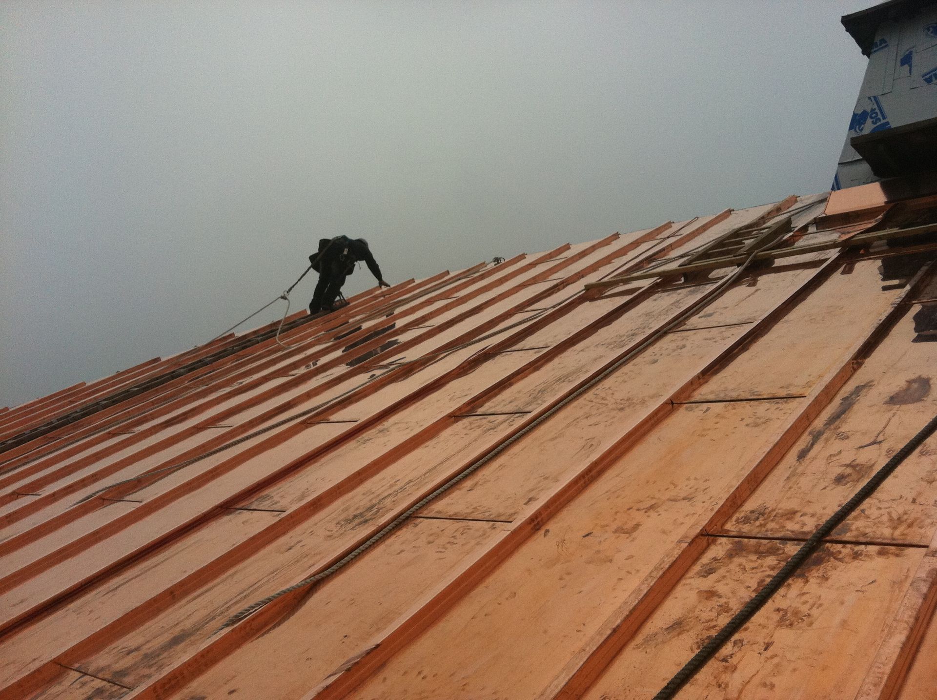 Un homme se tient au sommet d’un toit en bois