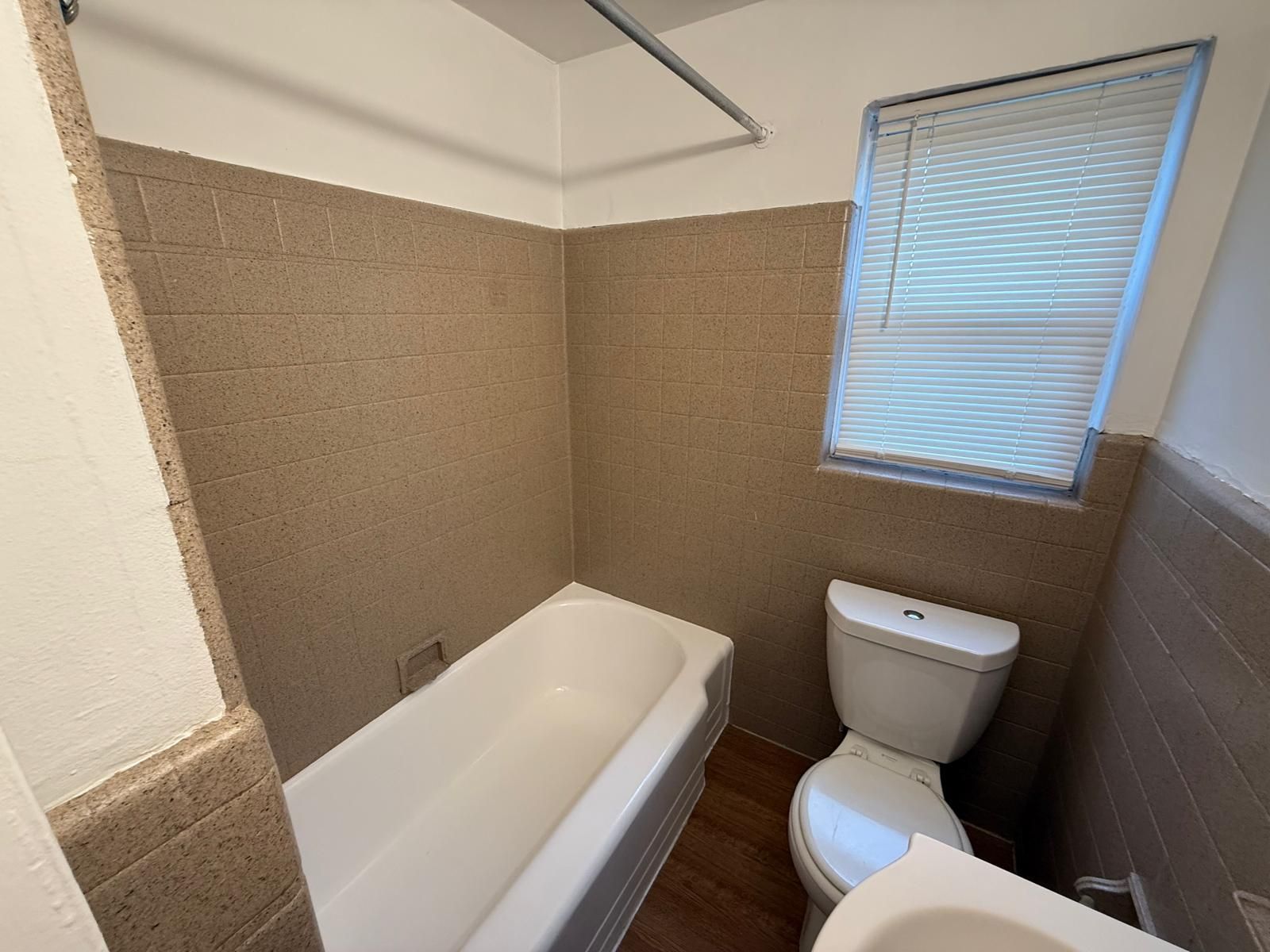 Bathroom with bathtub, tiled walls, and window at Maple Court Apartments