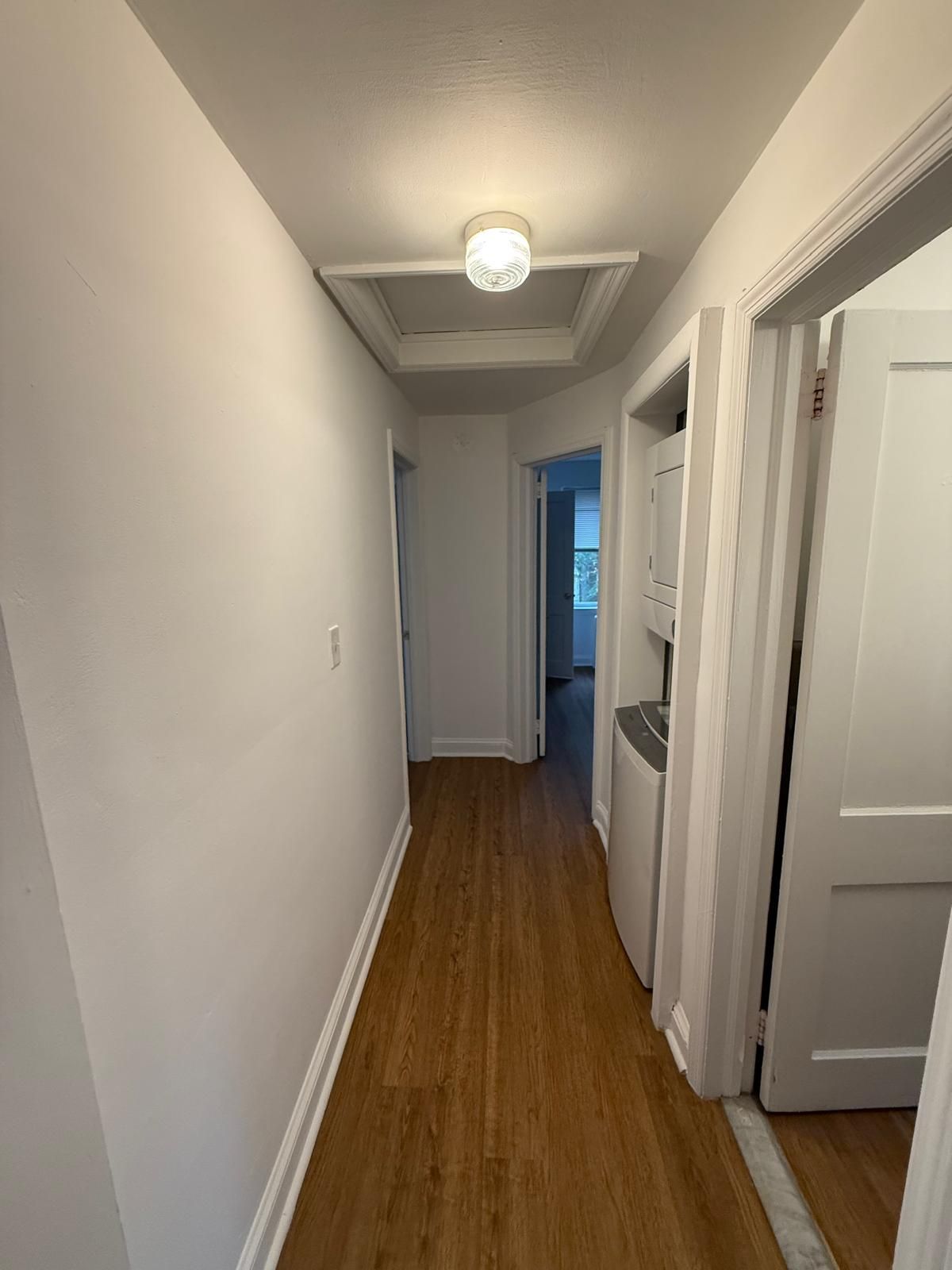 Bright apartment hallway leading to bedroom and living area
