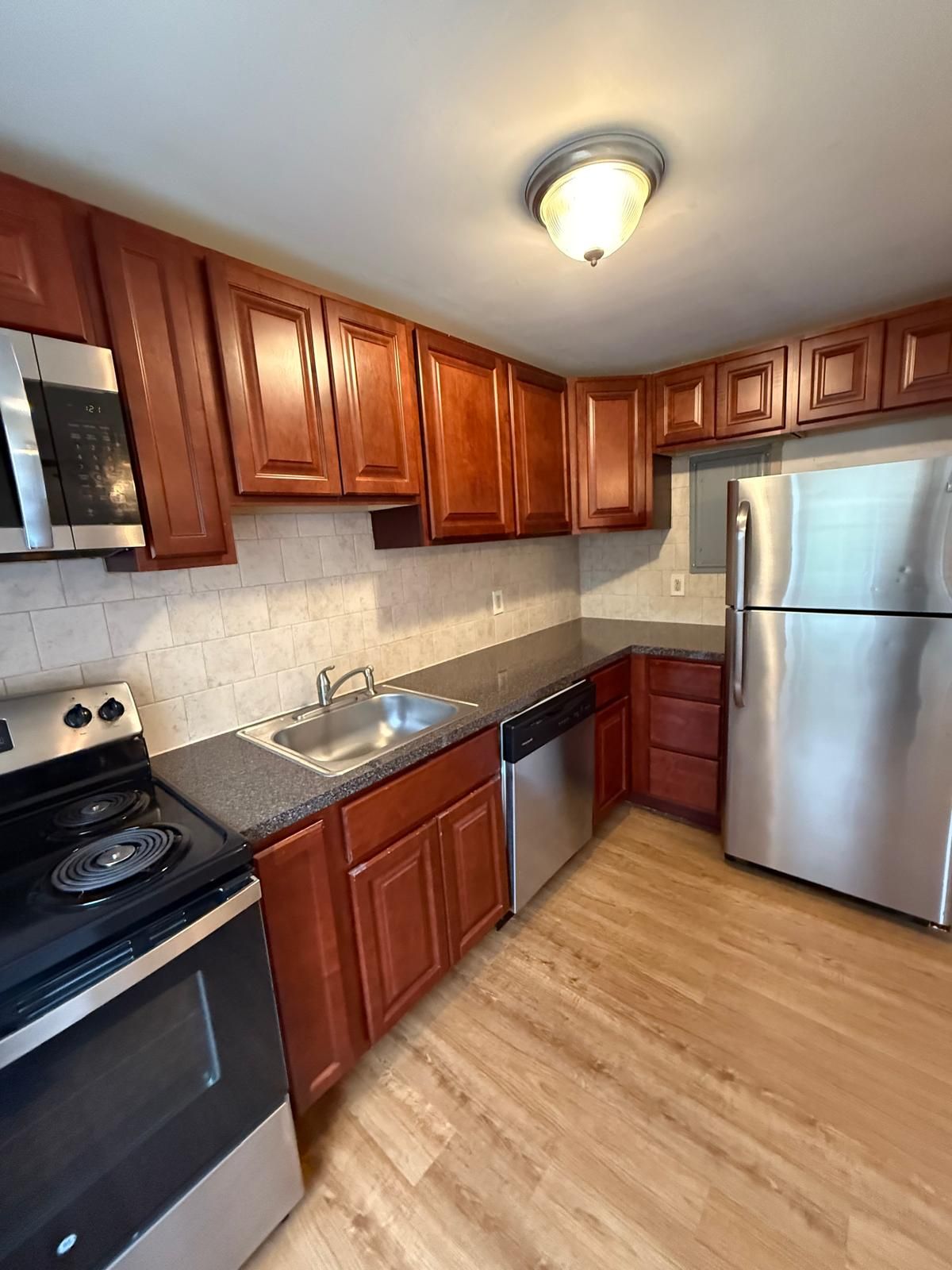 Kitchen with wooden cabinets and ceiling light at Maple Court Apartments
