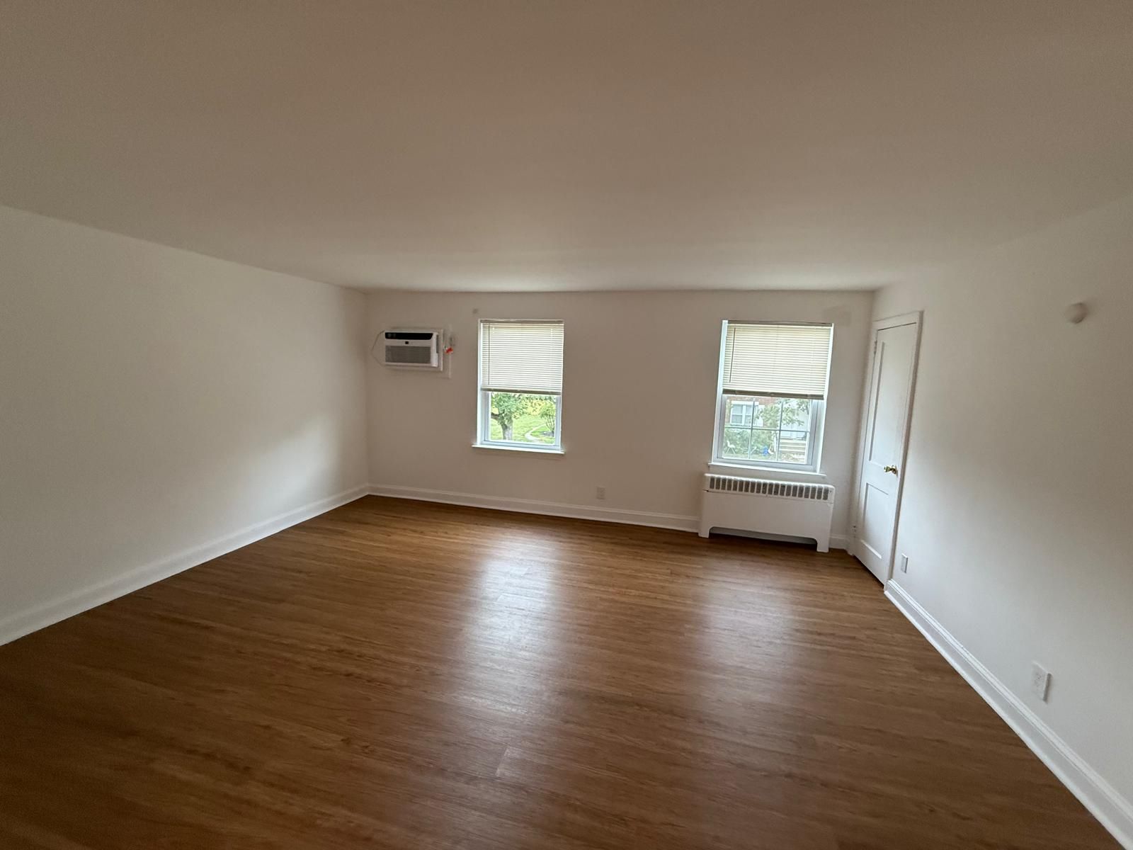 Spacious living room with natural light and hardwood flooring