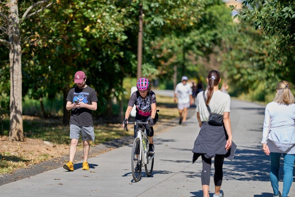 A group of people are walking and riding bikes on a path at Marq on Ponce.