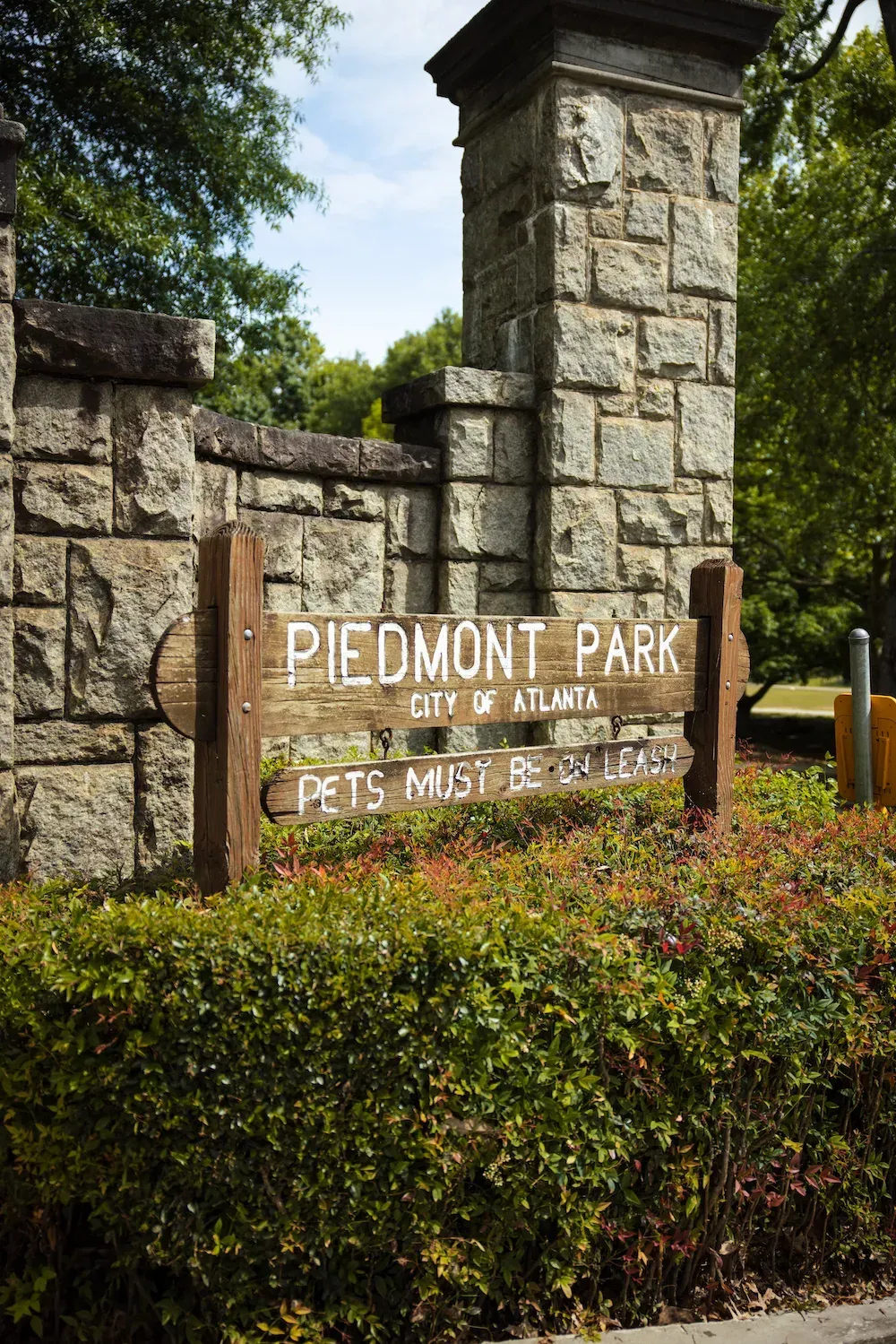 A wooden sign for piedmont park is sitting in front of a stone wall at Marq on Ponce.