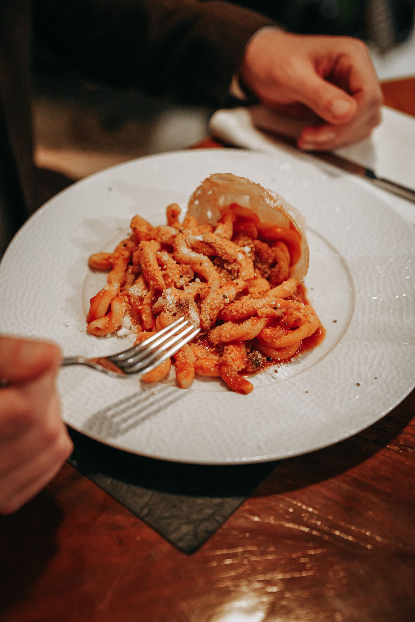 Persona che mangia pasta al sugo di pomodoro, usando una forchetta in un ristorante.