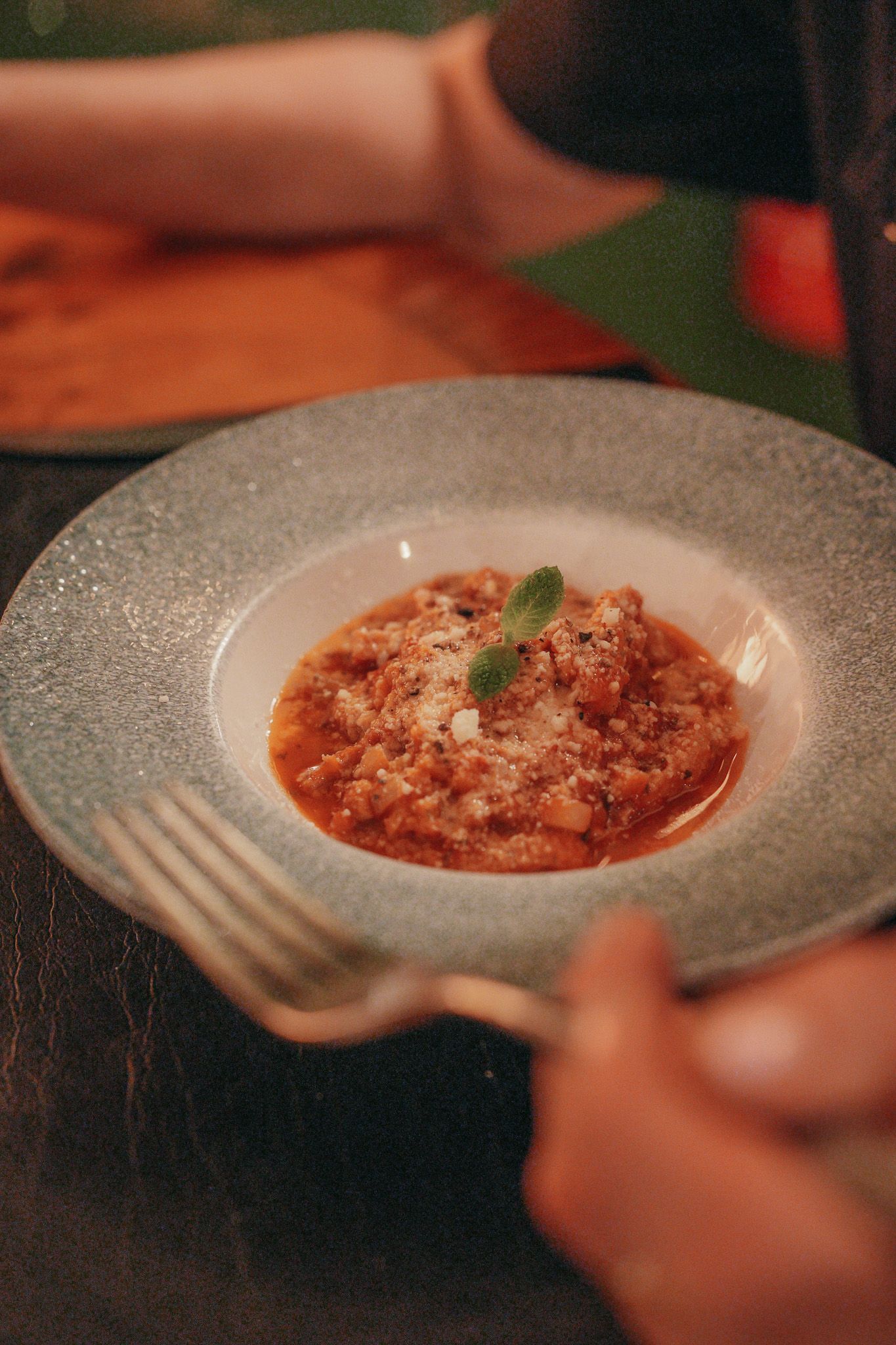 Piatto di pasta su un piatto con il bordo blu. Forchetta in mano.