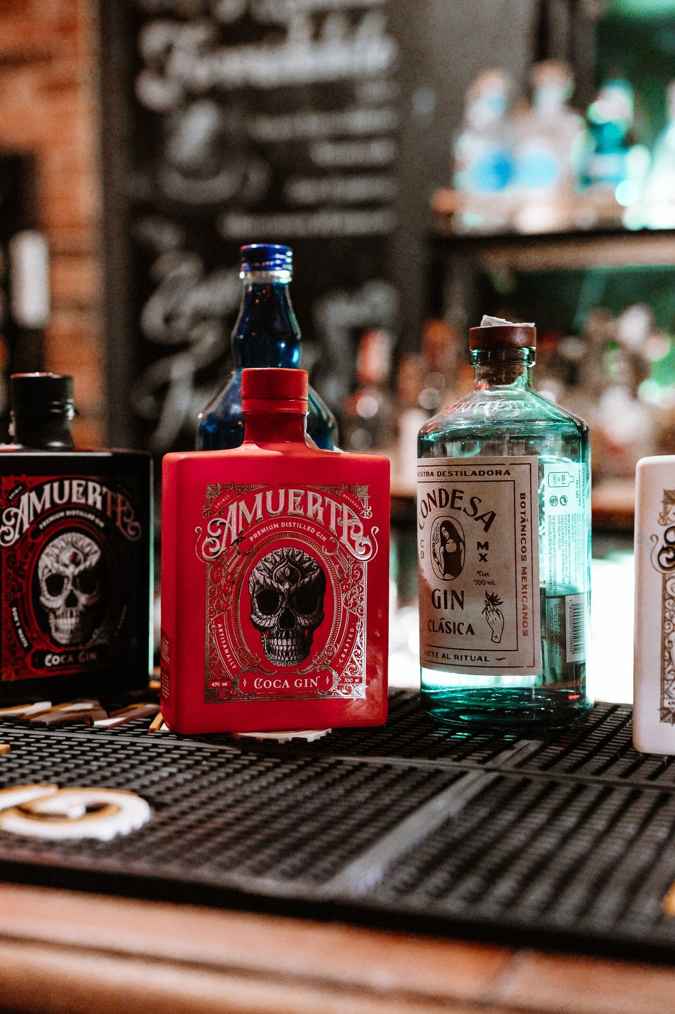 Bottiglie di liquore su un bancone: bottiglie rosse, blu e verdi con teschio e altre etichette.