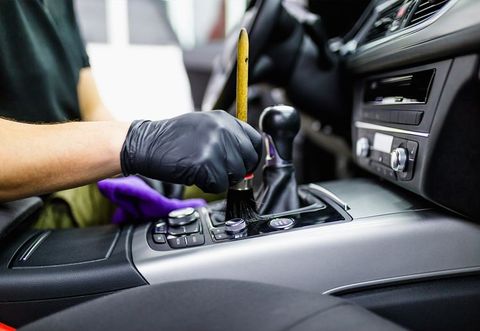 A man is cleaning the interior of a car with a brush.