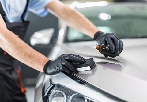 A man is polishing the hood of a car.