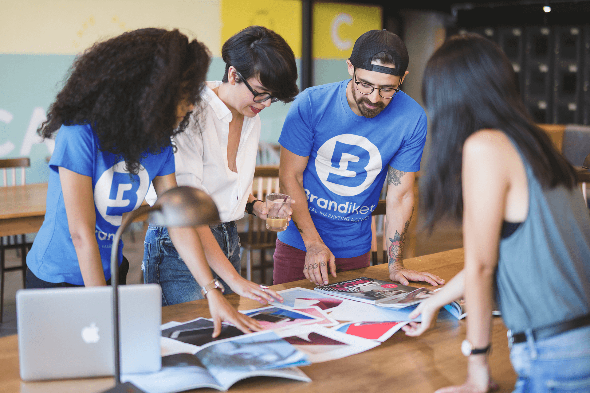 A group of people are standing around a table looking at magazines.