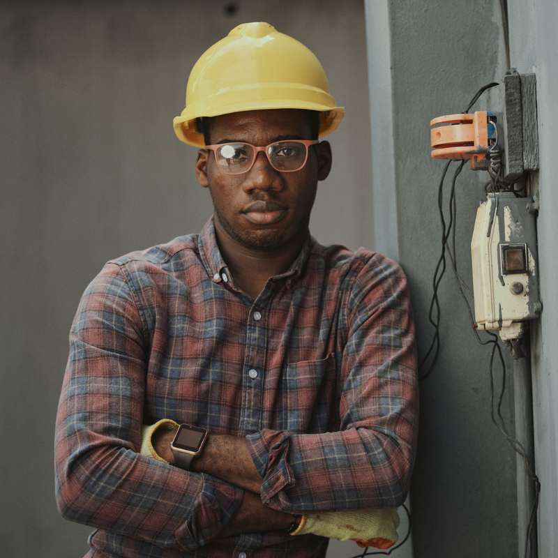 A man wearing a hard hat and glasses is standing with his arms crossed.