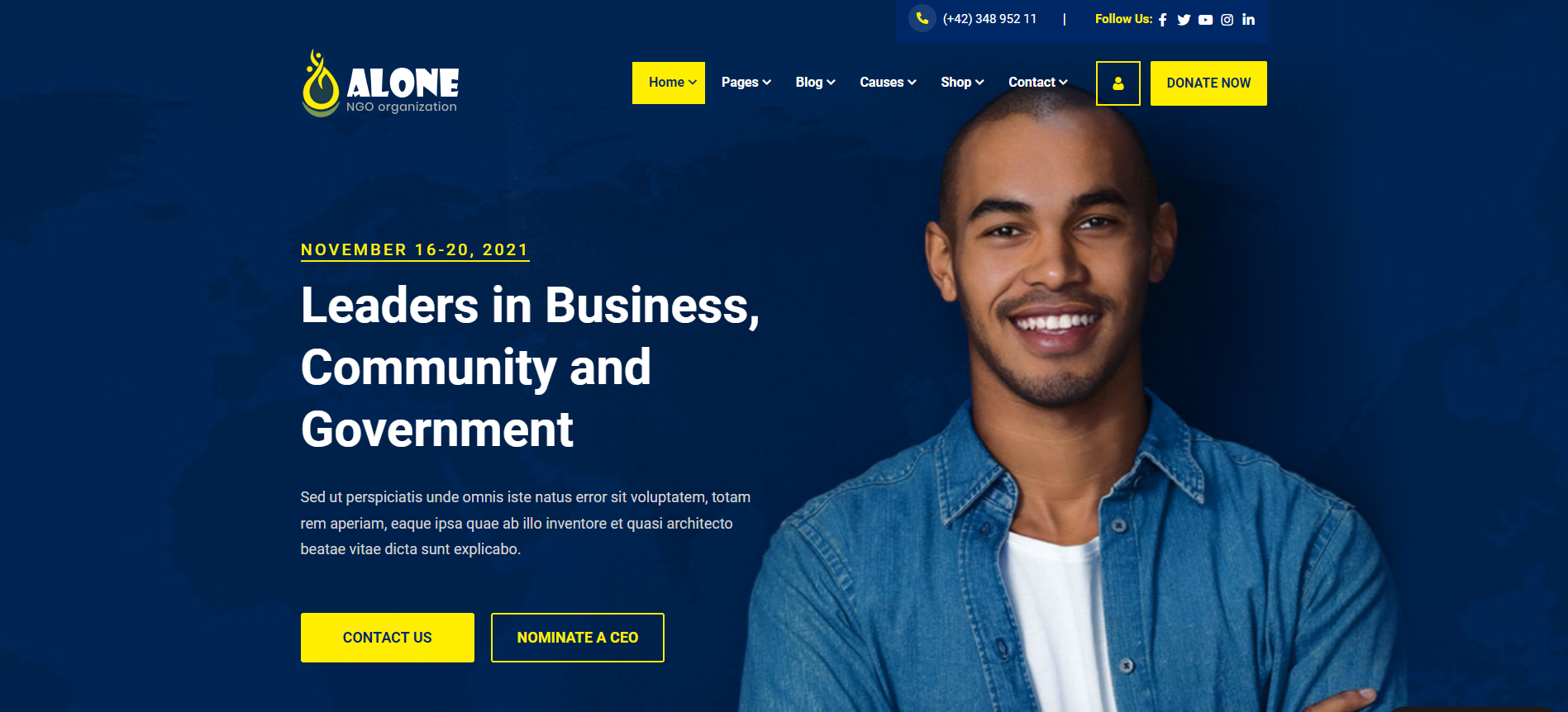 A man in a denim shirt is standing in front of a blue background.