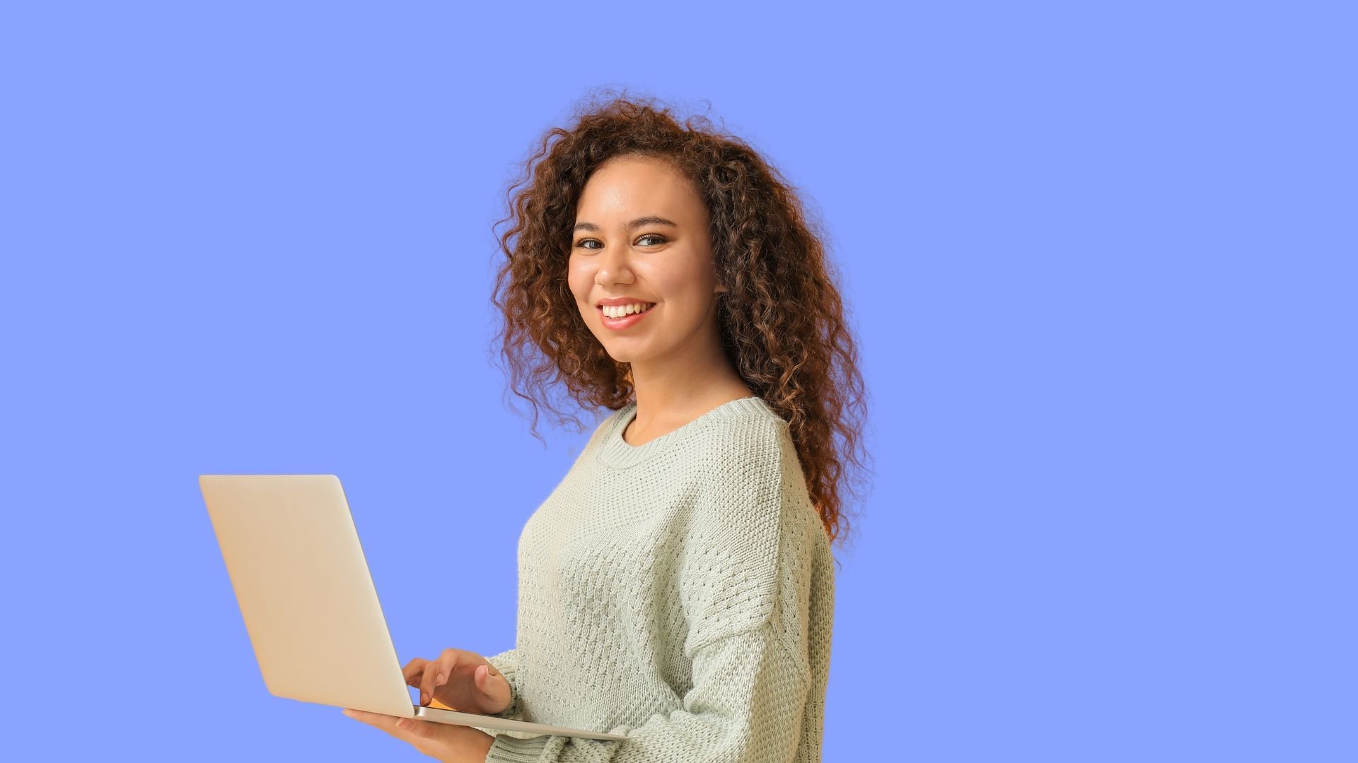 A woman is holding a laptop computer in her hands and smiling.