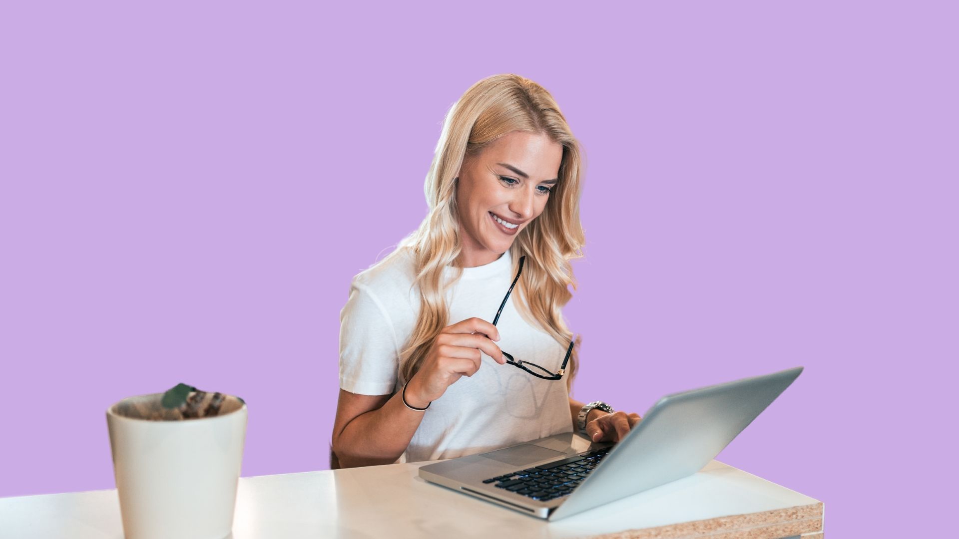 A woman is sitting at a table using a laptop computer.