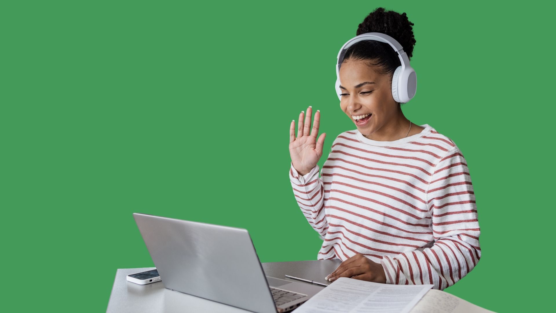 A woman wearing headphones is sitting at a desk using a laptop computer.