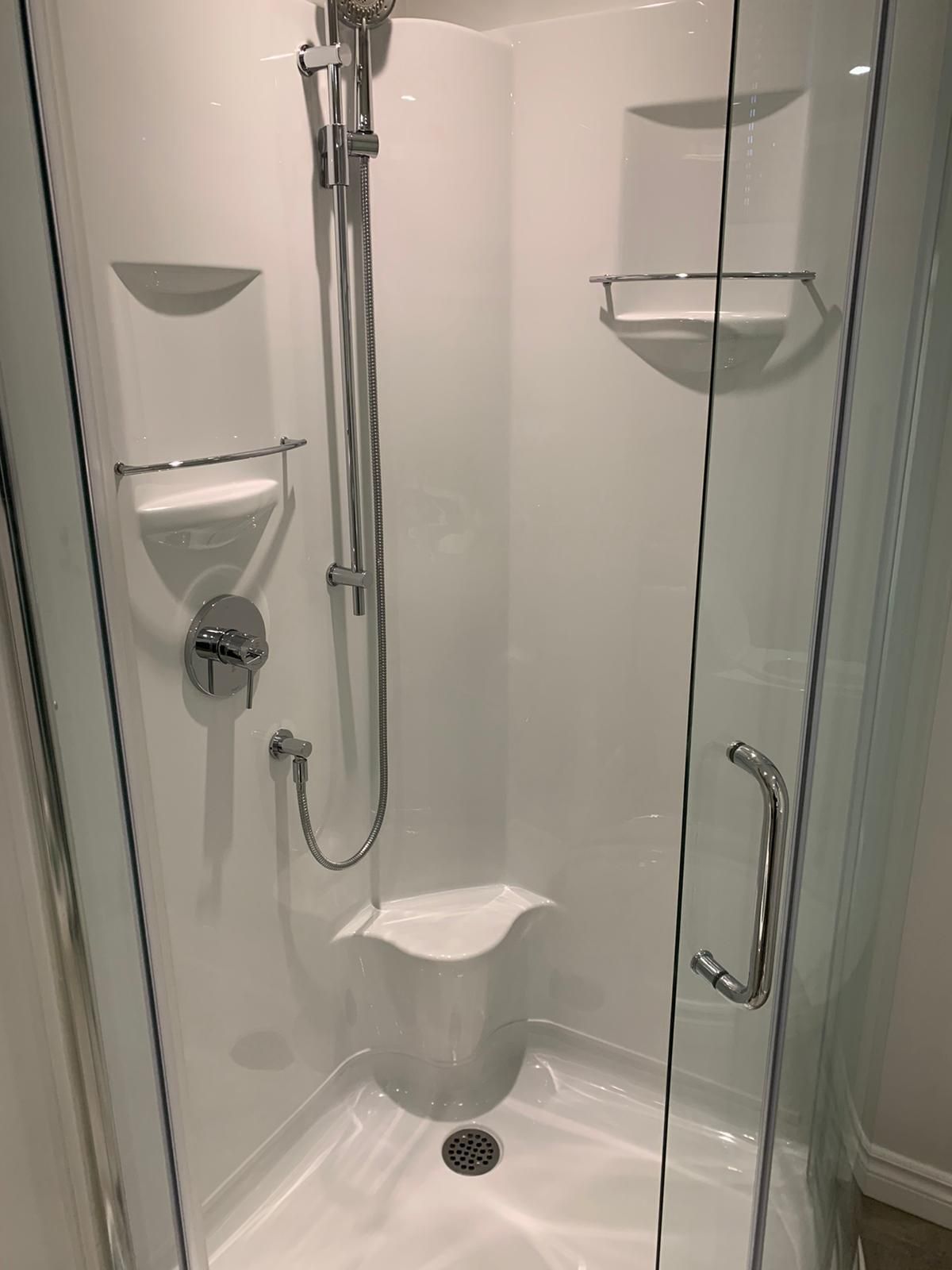 Une cabine de douche avec un siège et une pomme de douche dans une salle de bain.