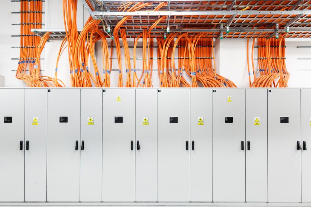 A Row of White Cabinets with Orange Wires Hanging from The Ceiling — A & J Electrical Contractors in Tamworth, NSW