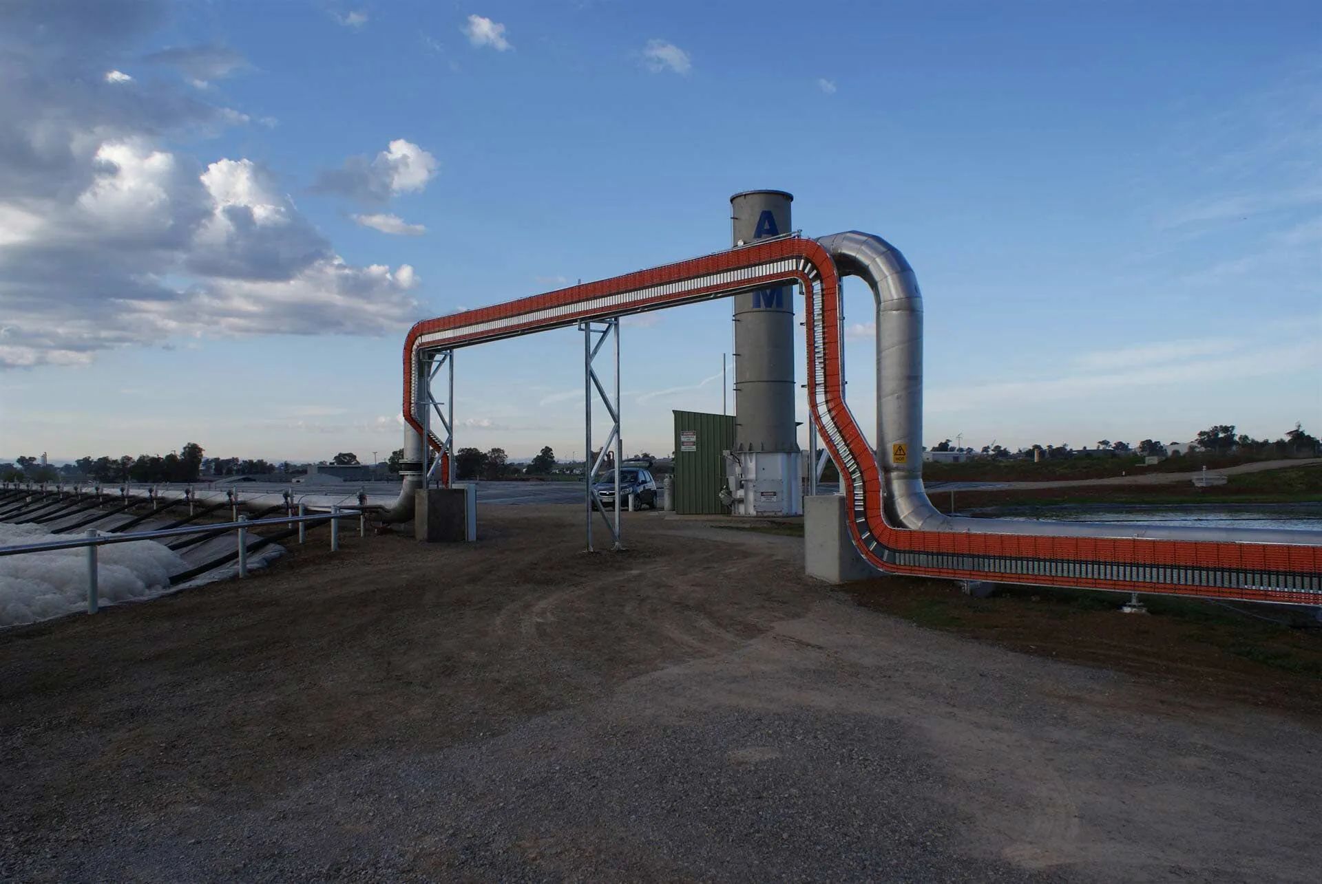 Solar Farm Infrastructure with Curved Pipes and Tall Tower Under Blue Sky — A & J Electrical Contractors in Tamworth, NSW
