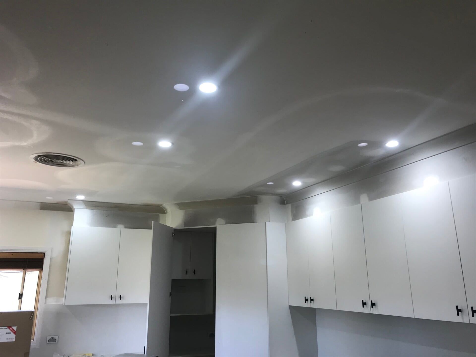 A Kitchen with White Cabinets and Lights on The Ceiling — A & J Electrical Contractors in Taminda, NSW