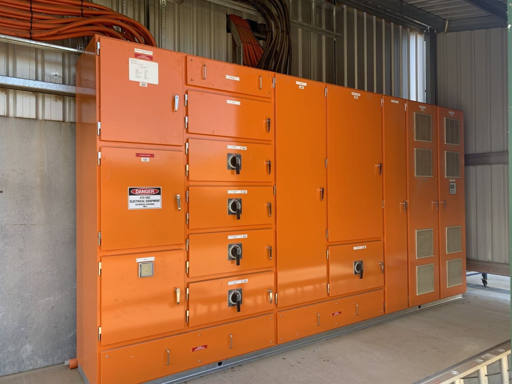 A Row of Orange Cabinets with A Warning Sign on Them — A & J Electrical Contractors in Taminda, NSW