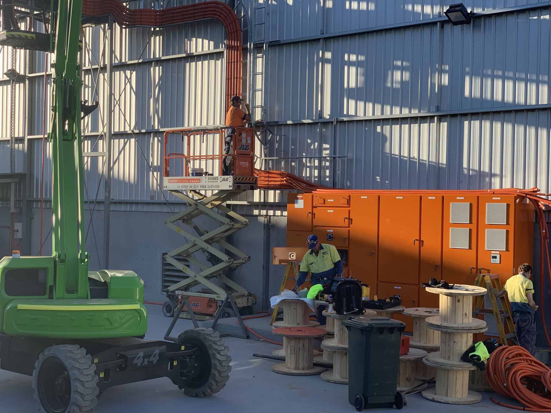 A Green Construction Vehicle Is Parked in Front of A Building — A & J Electrical Contractors in Taminda, NSW