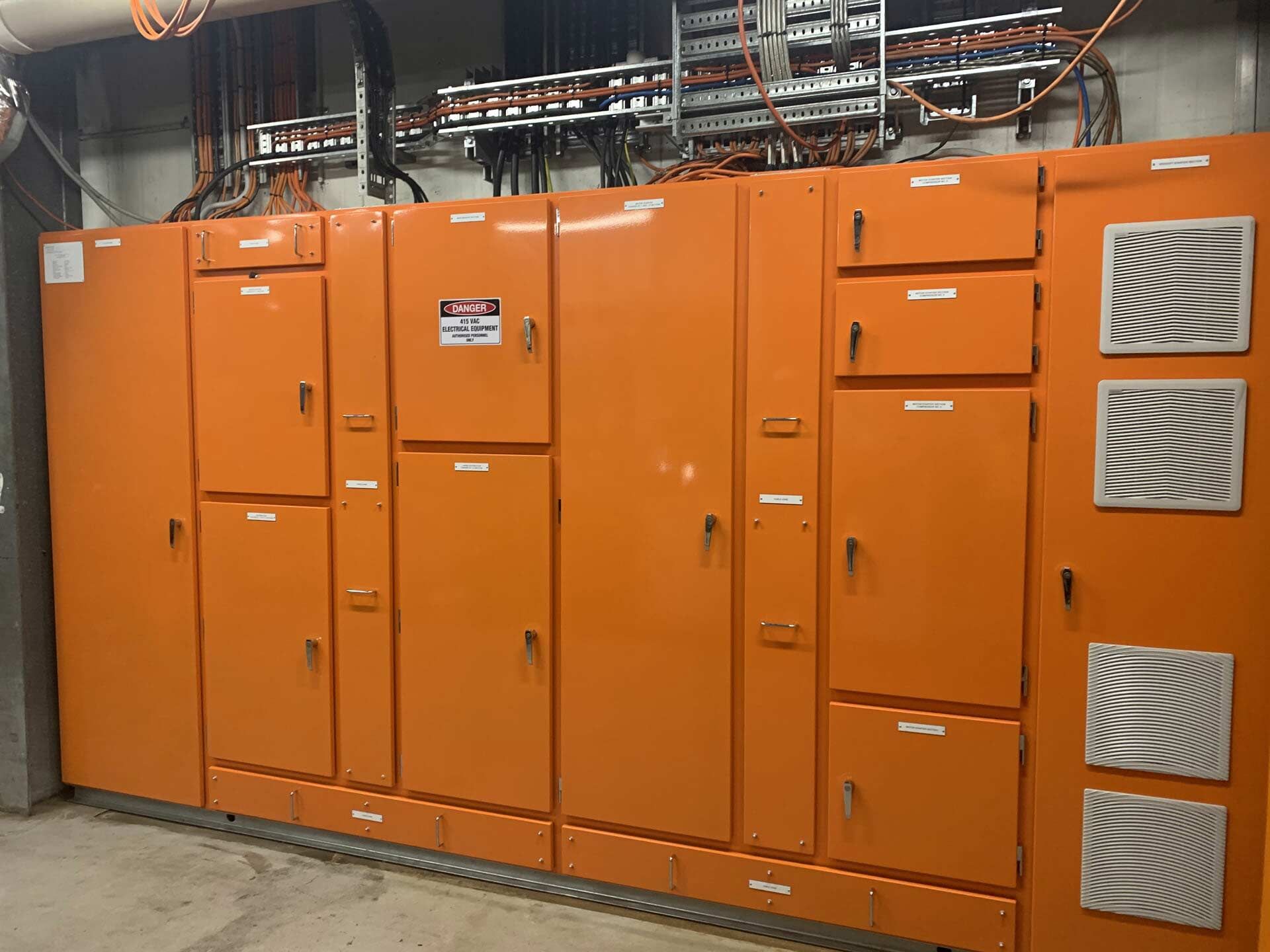 A Row of Orange Electrical Cabinets in A Room — A & J Electrical Contractors in Taminda, NSW