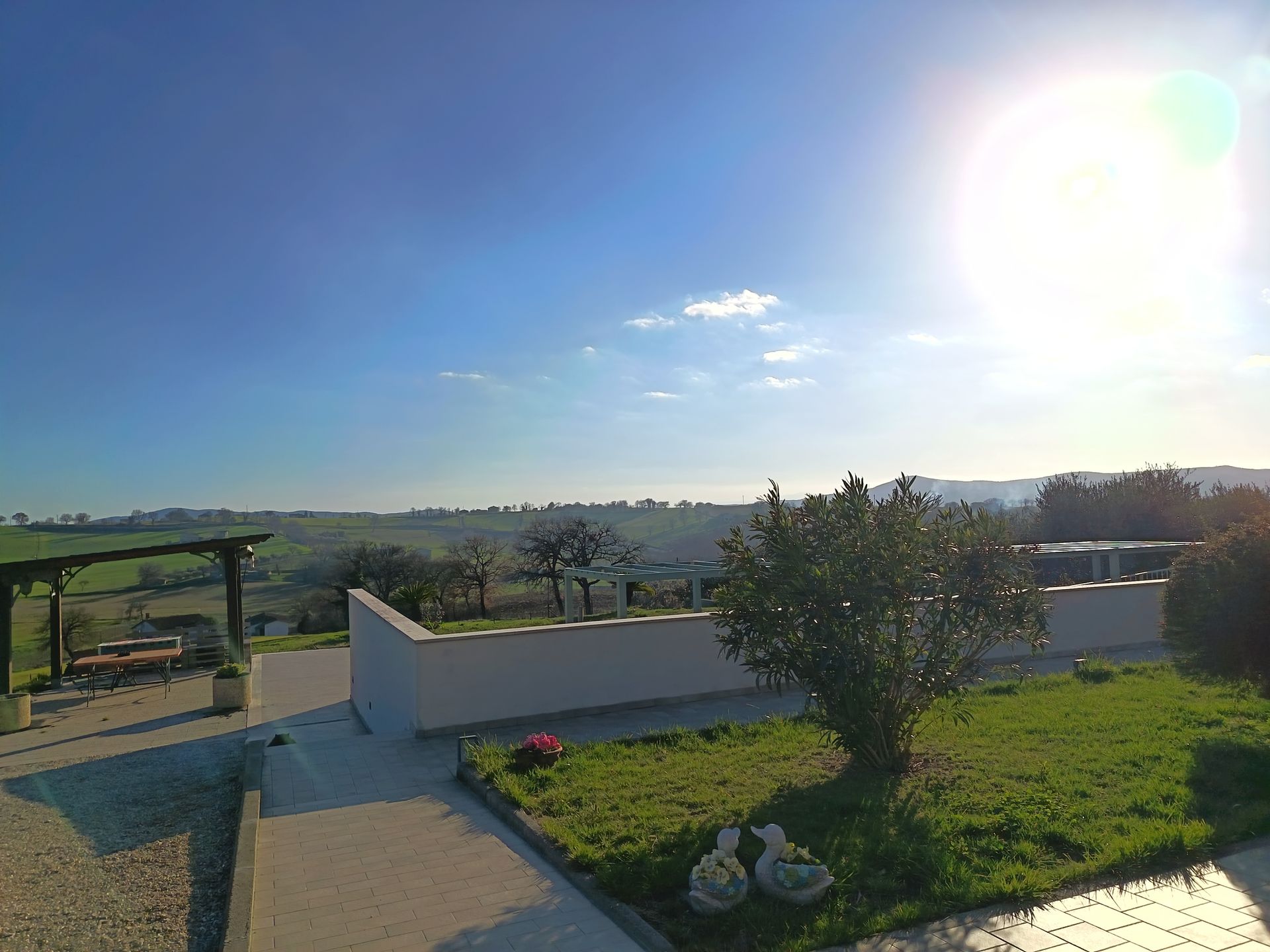 Un patio soleggiato si affaccia su un paesaggio verdeggiante e ondulato