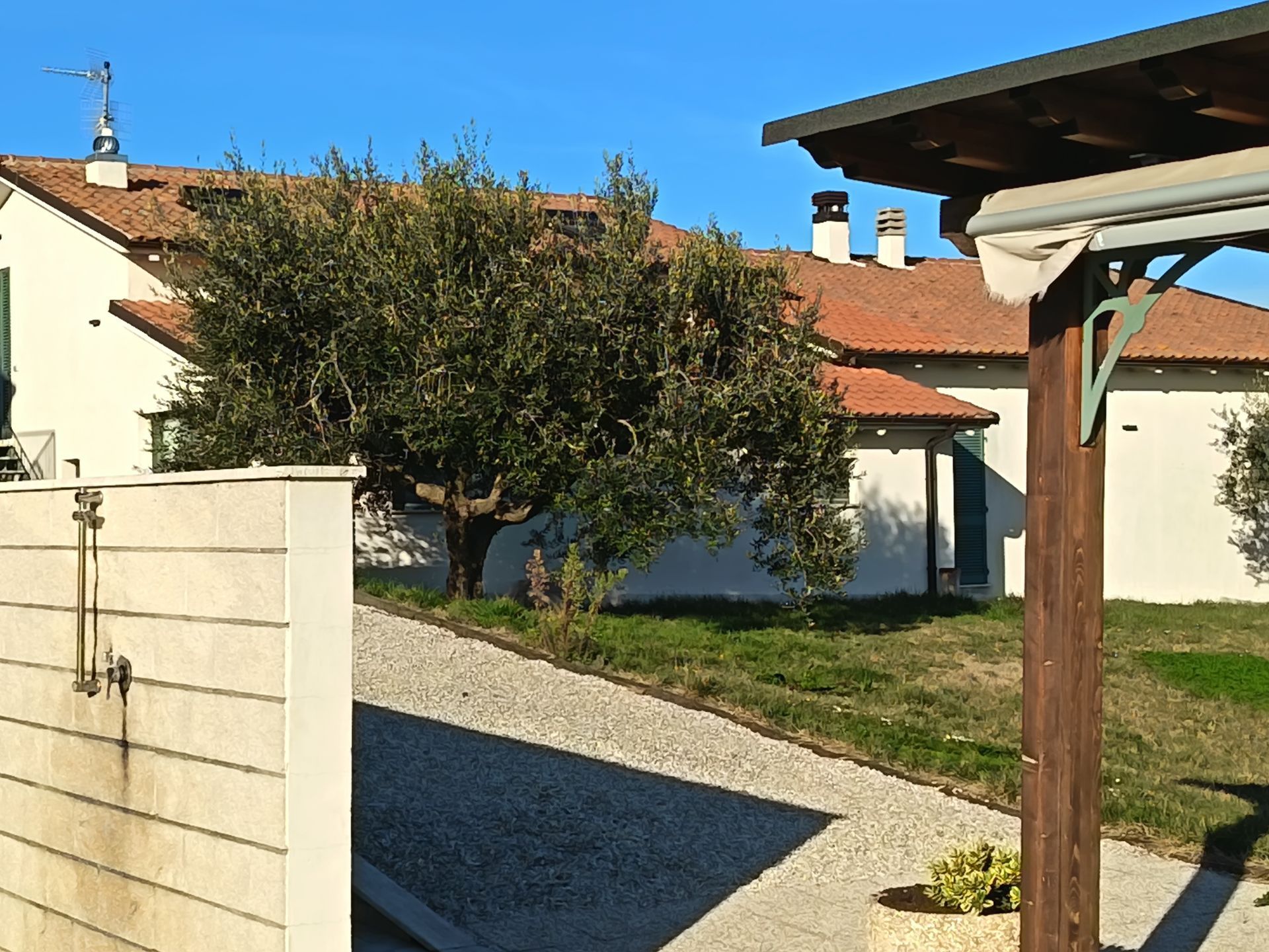 Un vialetto di ghiaia conduce a un edificio di colore chiaro con tetto in terracotta