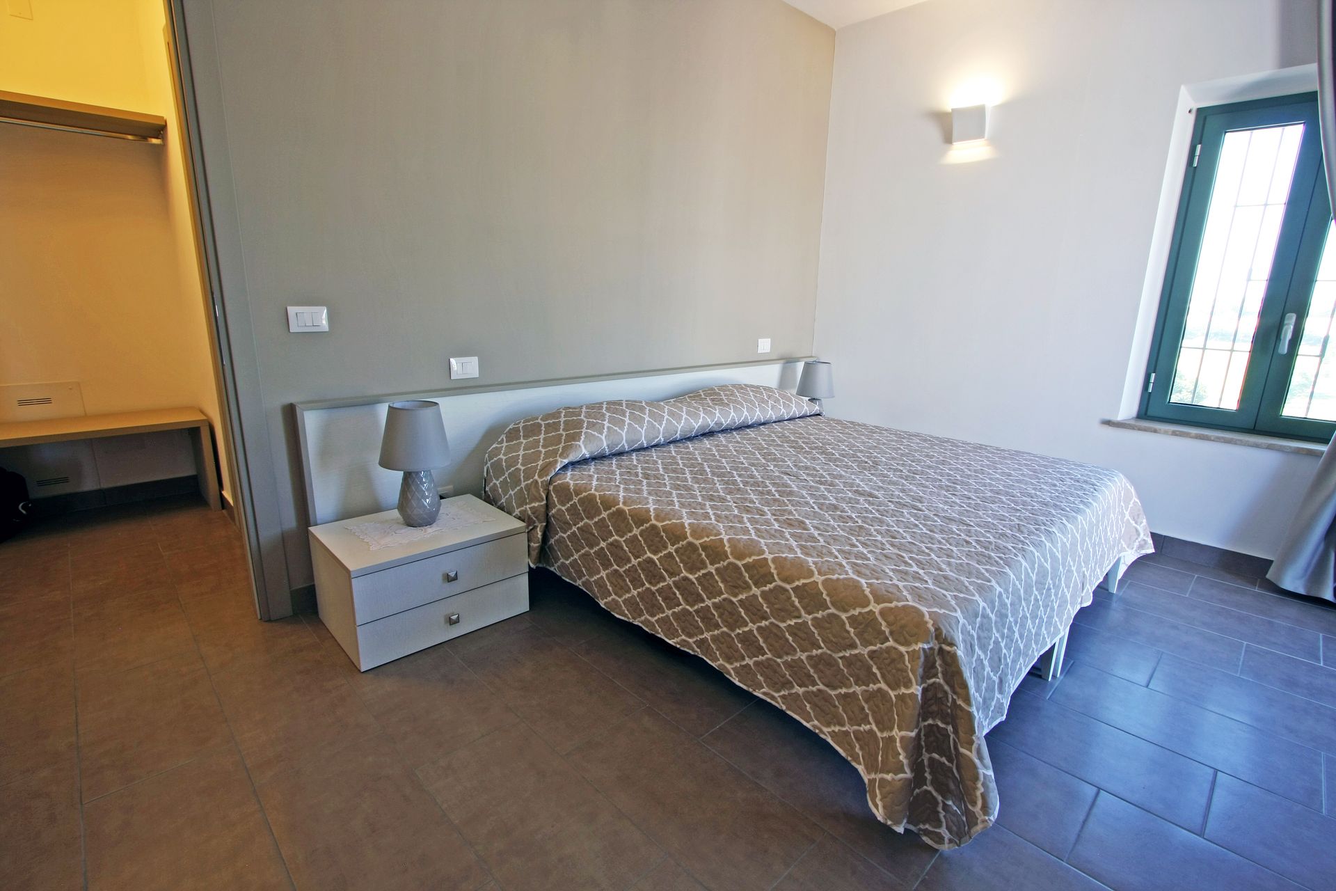 Una camera d'albergo con un letto matrimoniale queen-size con copriletto beige a fantasia,