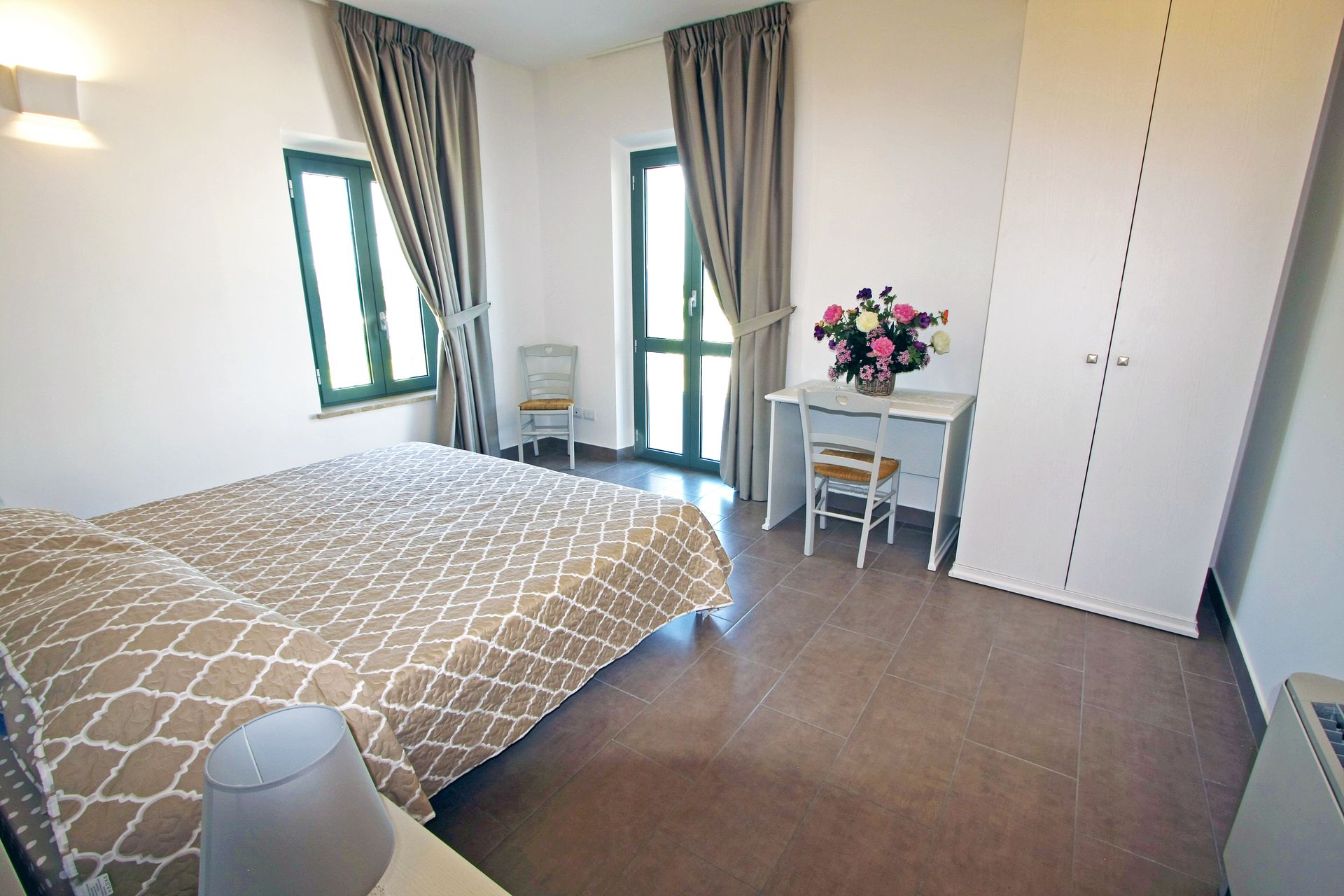 Una camera da letto pulita e dai colori neutri, con un copriletto a fantasia