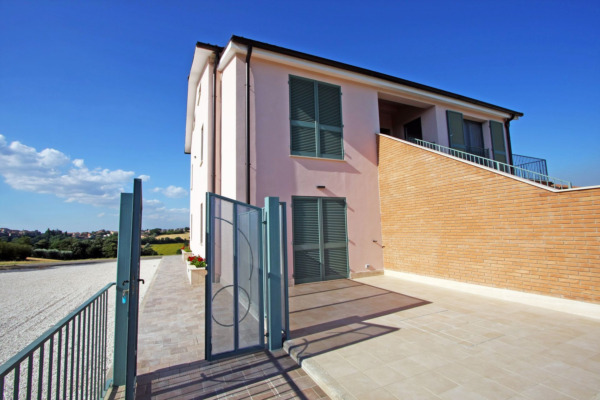 Un edificio rosa pallido a due piani con persiane verdi