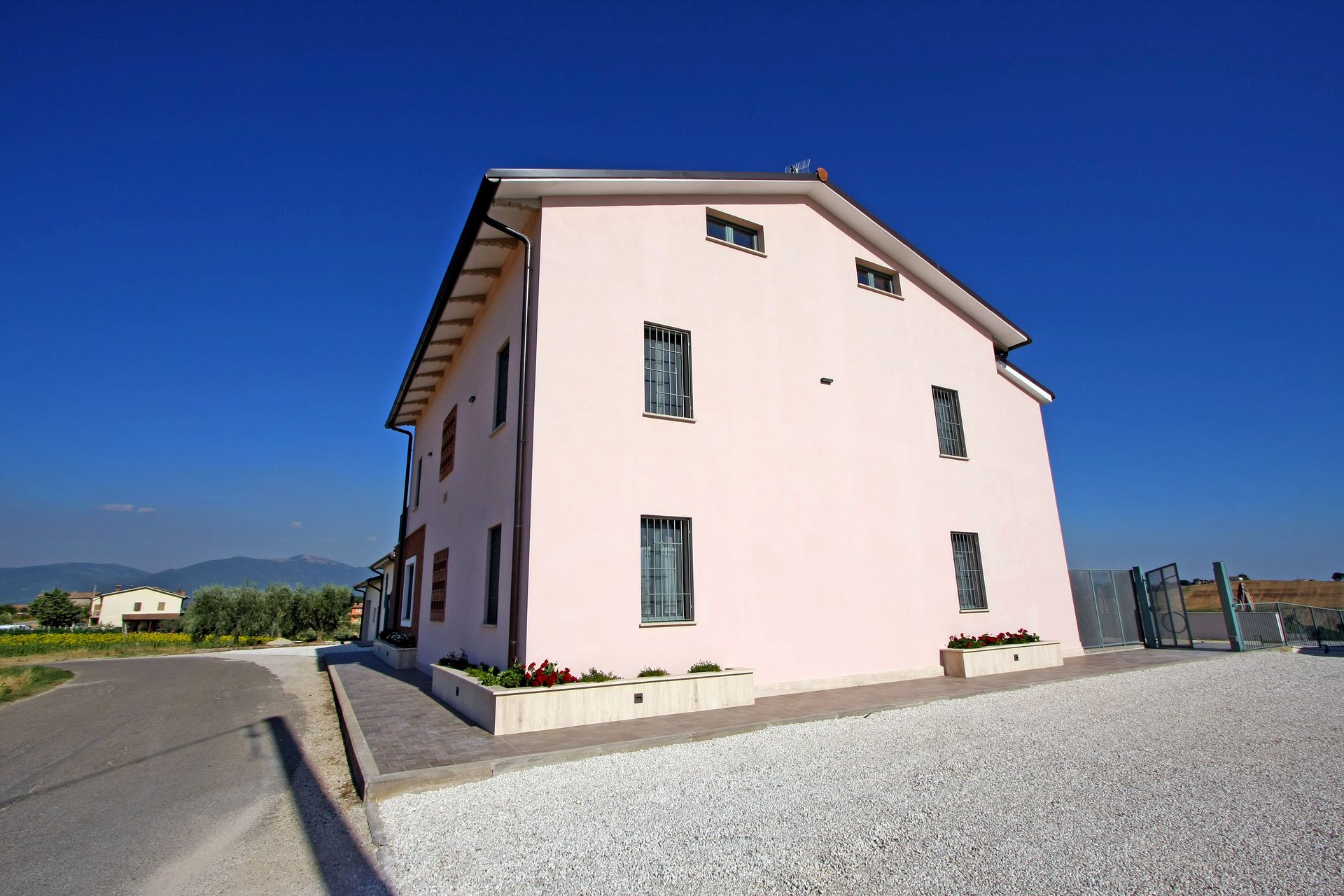 Un edificio a due piani di colore rosa pallido sotto un cielo azzurro limpido