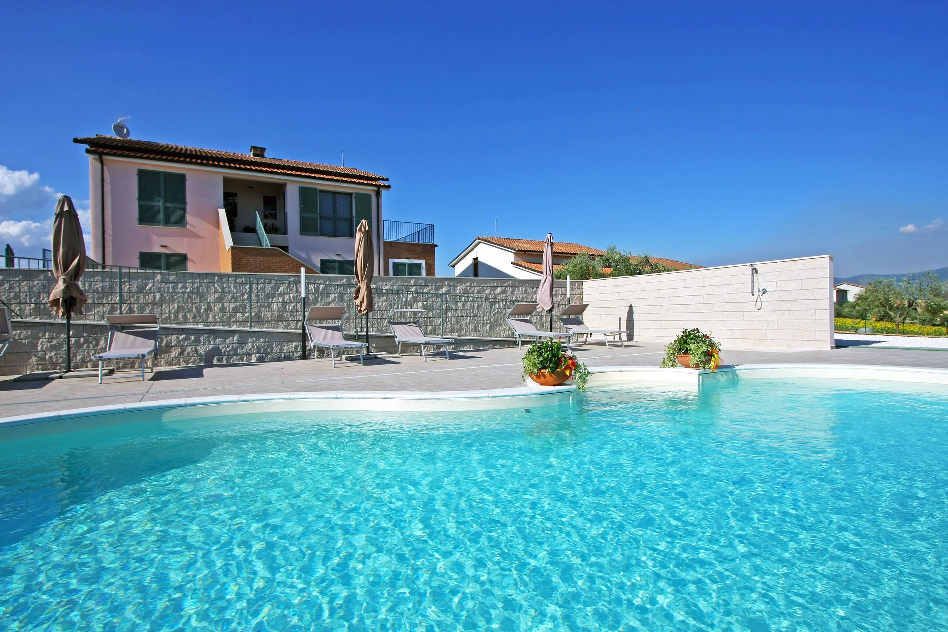 In primo piano una piscina di un blu brillante, sullo sfondo una casa rosa