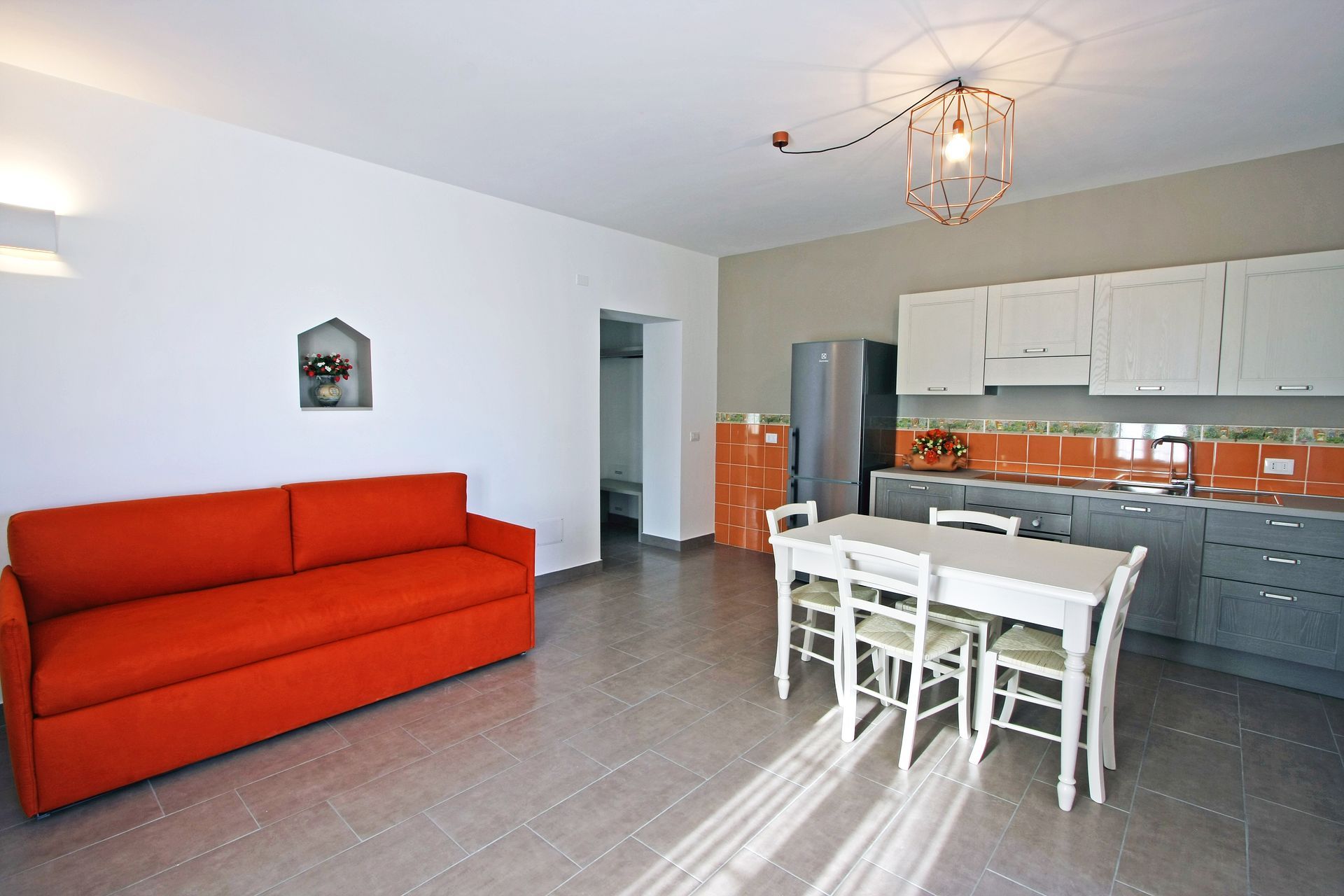 Una moderna cucina e zona giorno con un divano arancione acceso