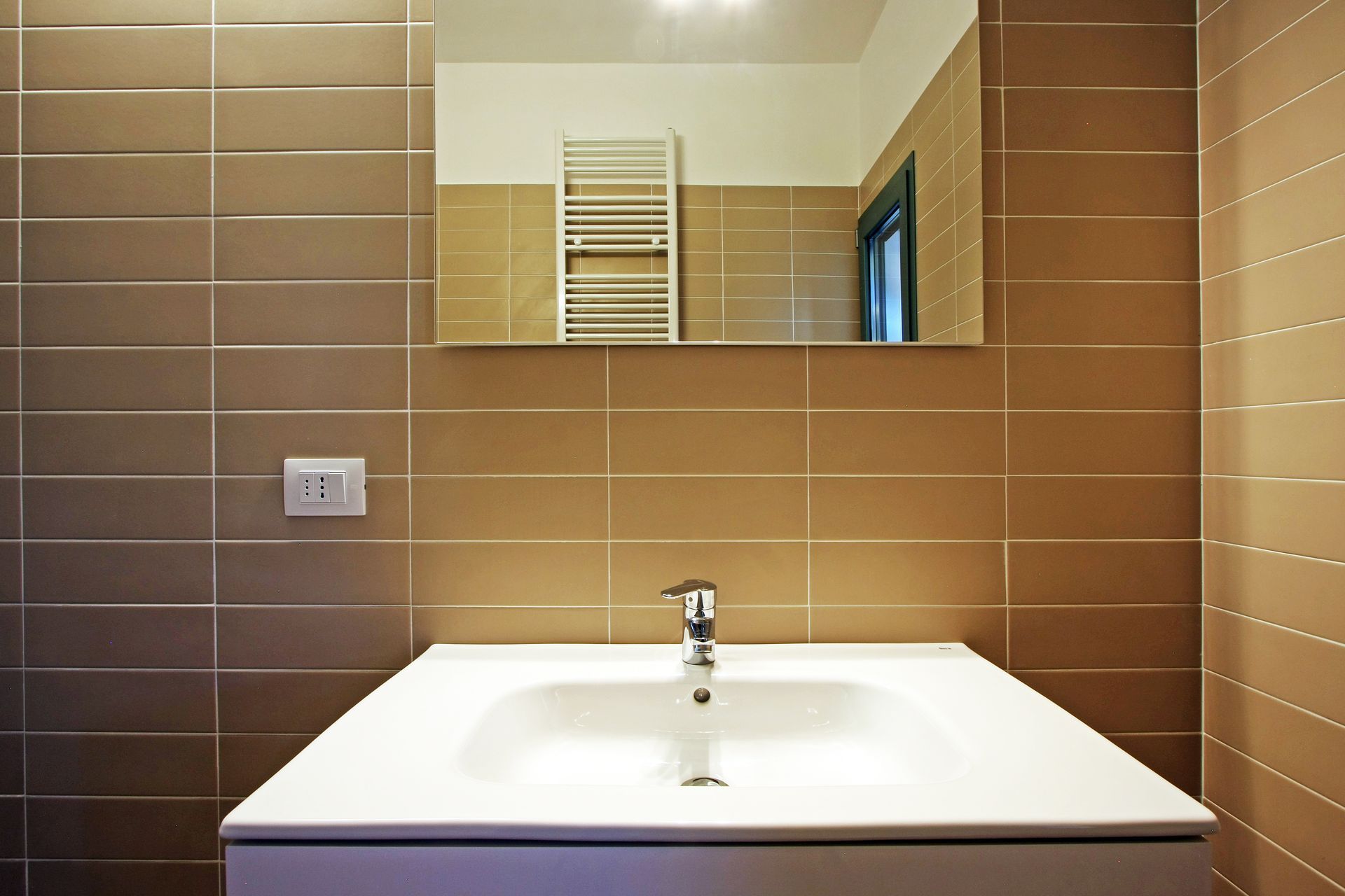 Un lavabo e un rubinetto bianchi per il bagno, montati su una parete 