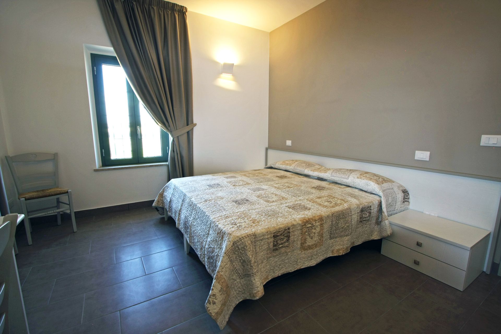 Una camera d'albergo con un letto matrimoniale, una trapunta a fantasia