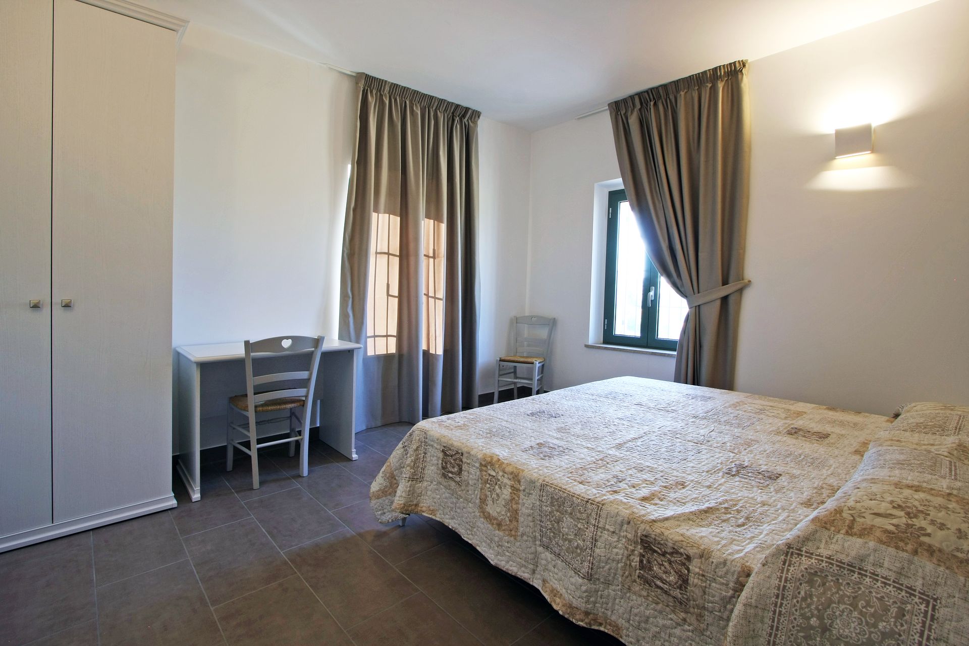 Una camera d'albergo con un letto matrimoniale, una scrivania con sedia