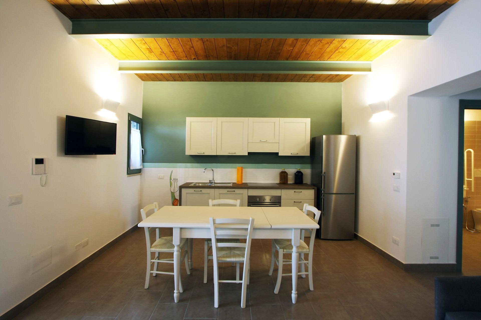 Un tavolo da pranzo con quattro sedie bianche si trova di fronte a una piccola zona