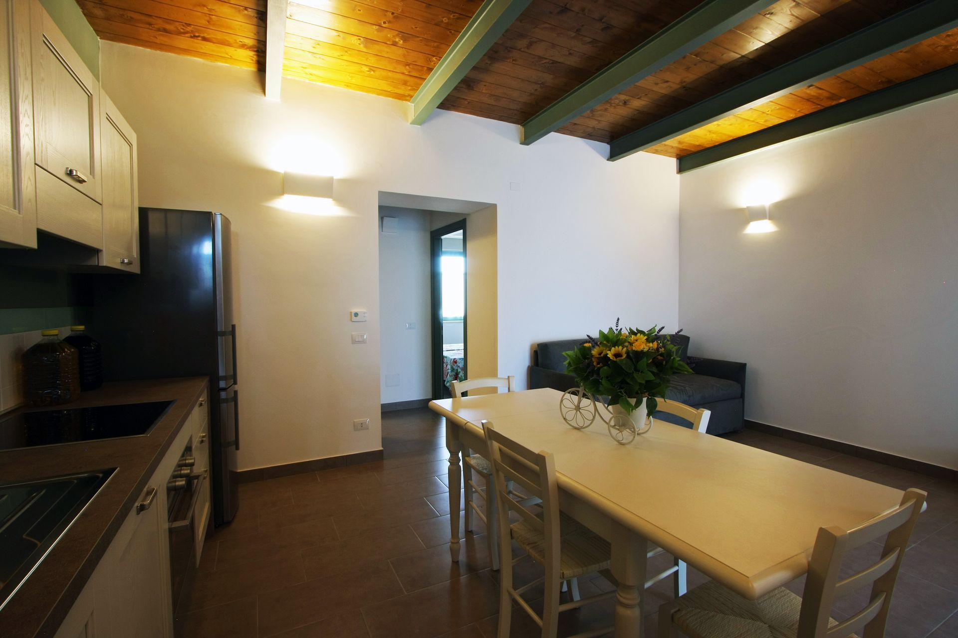 Una cucina con zona pranzo
, un tavolo da pranzo con fiori e un divano sullo sfondo.