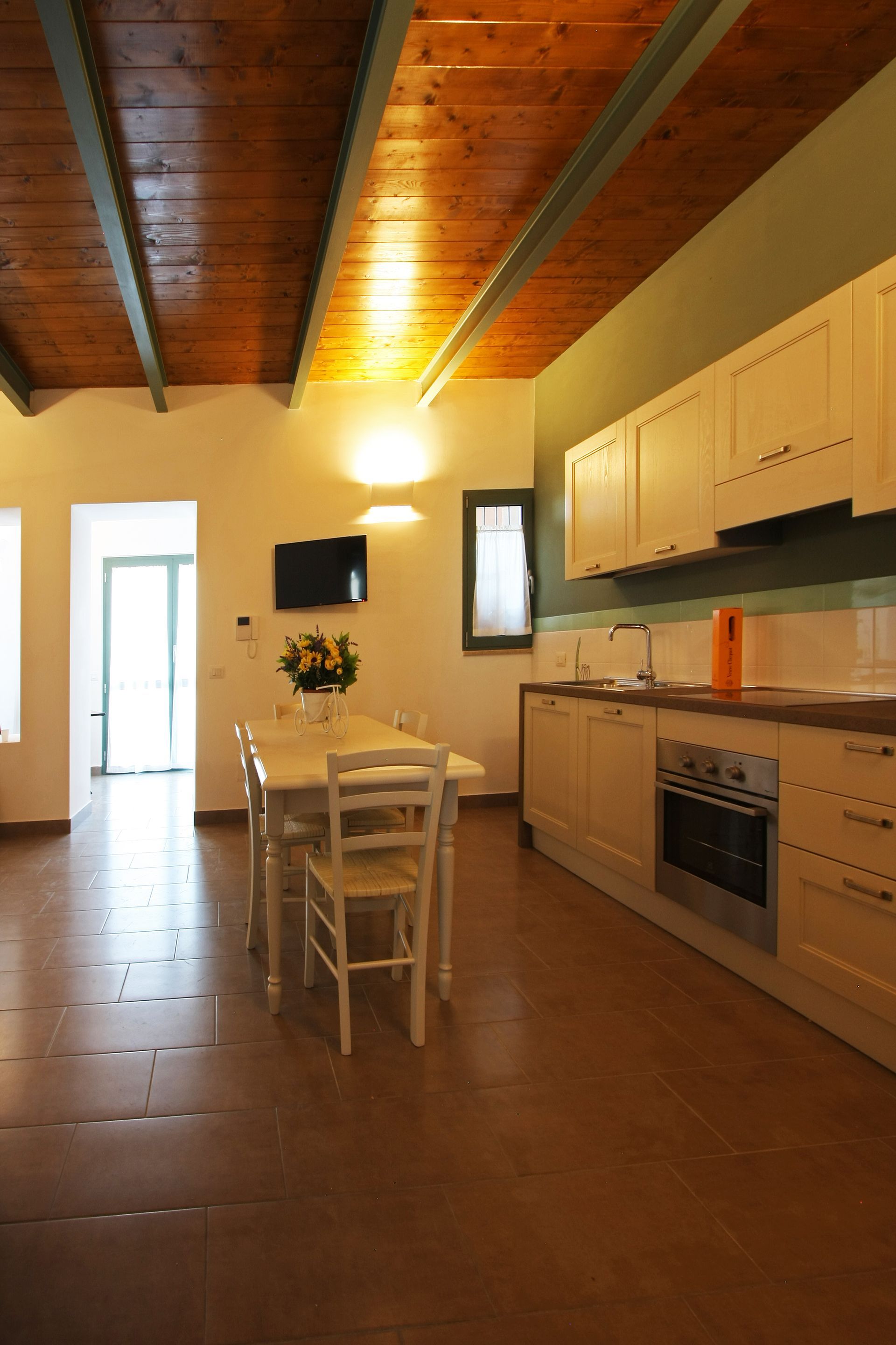 Una luminosa cucina con zona pranzo, caratterizzata da un soffitto con travi in legno