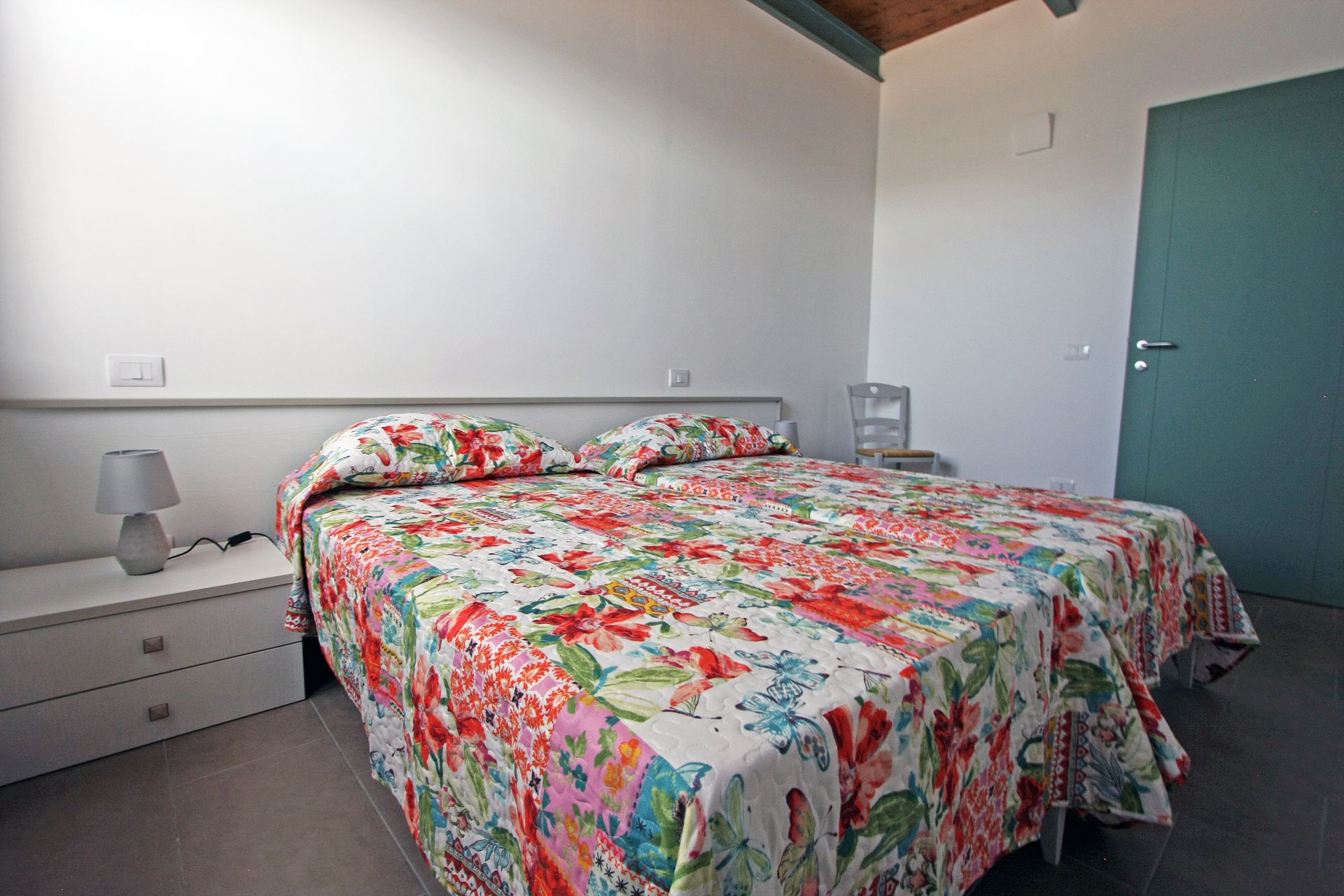 Una camera da letto luminosa con un letto matrimoniale con una trapunta dai colori vivaci