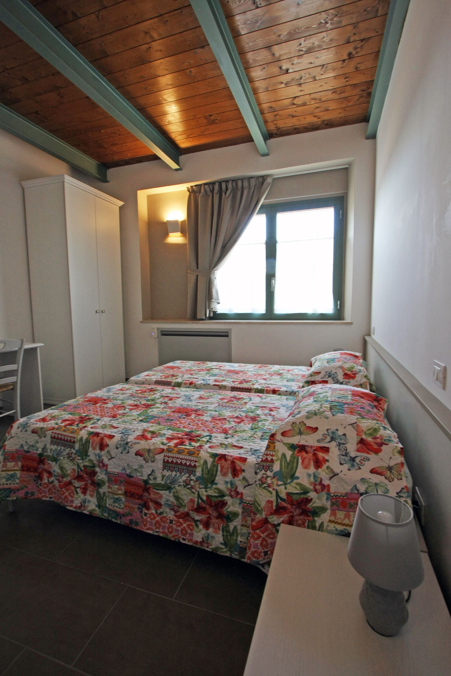 Una camera da letto con un letto a motivi floreali, travi in legno a vista sul soffitto