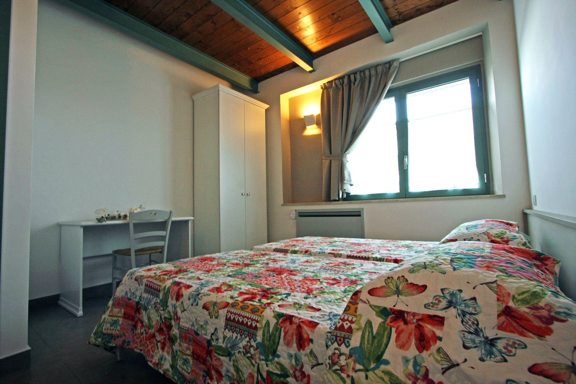 Una camera da letto con un letto a motivi floreali, una scrivania bianca con sedia