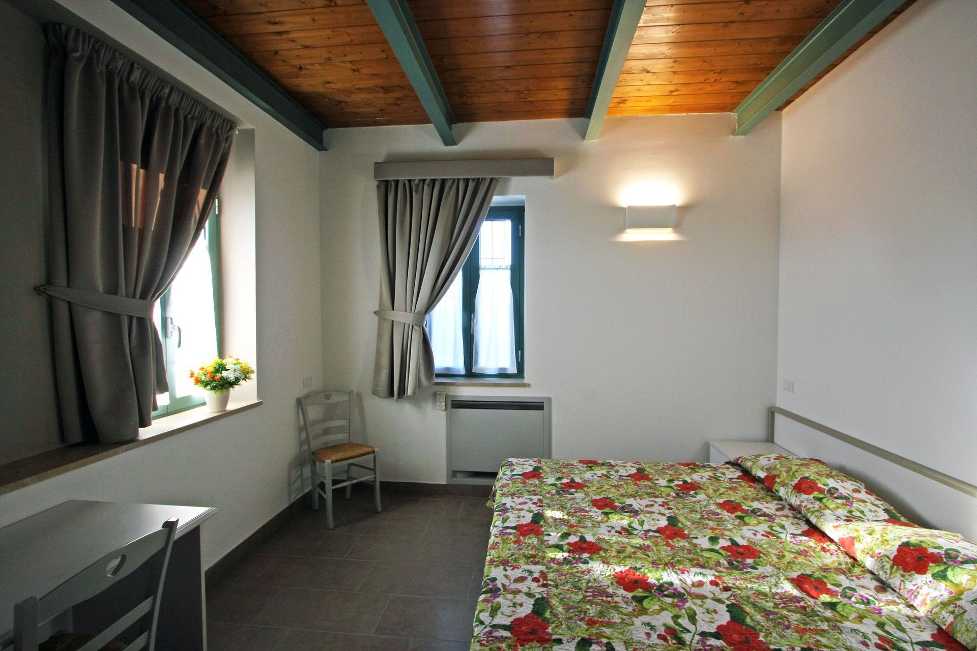 Una semplice camera da letto con un copriletto a fiori