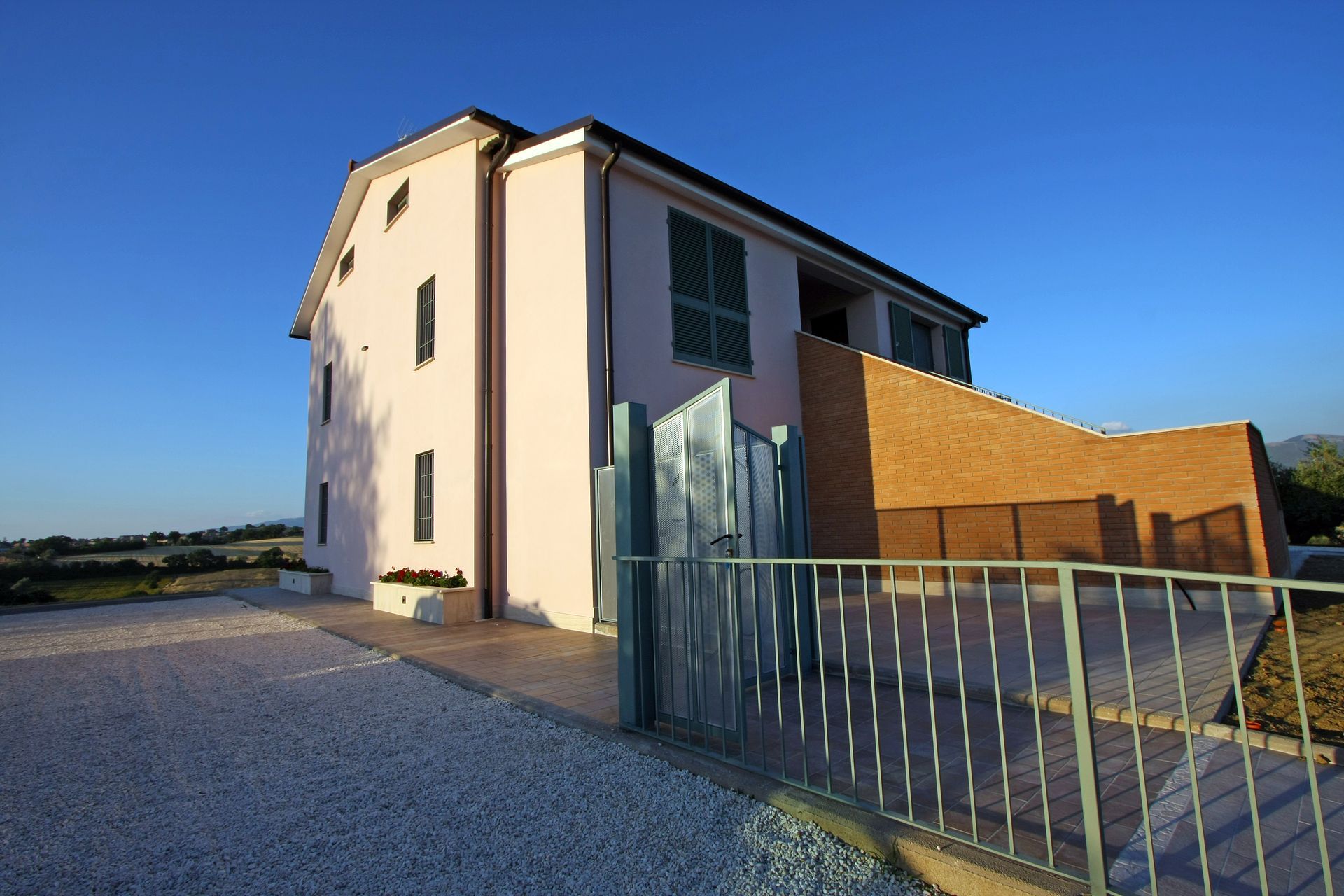 Una casa a due piani color rosa chiaro con una parete decorativa in mattonI