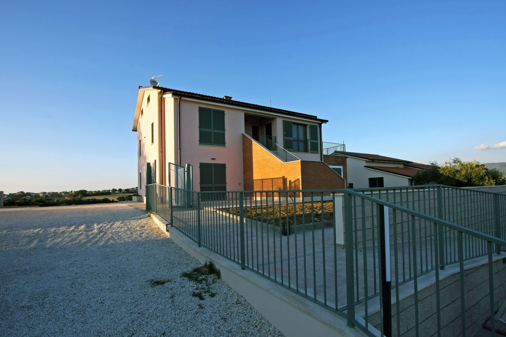 Una casa a due piani di colore rosa chiaro con persiane verde scuro