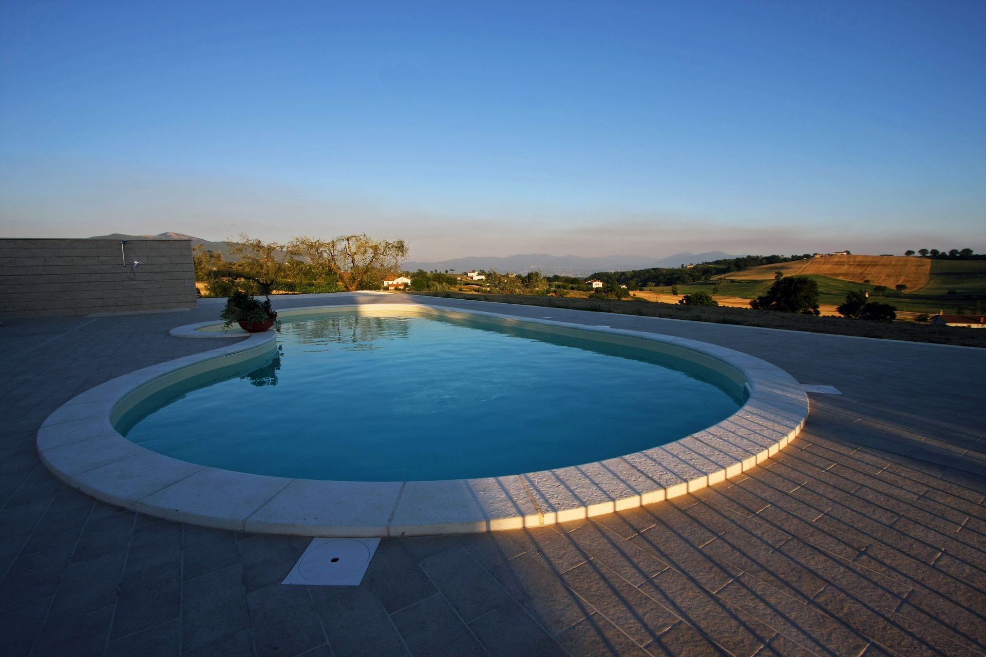 Una piscina a forma di rene con acqua azzurra sorge su un patio in pietra