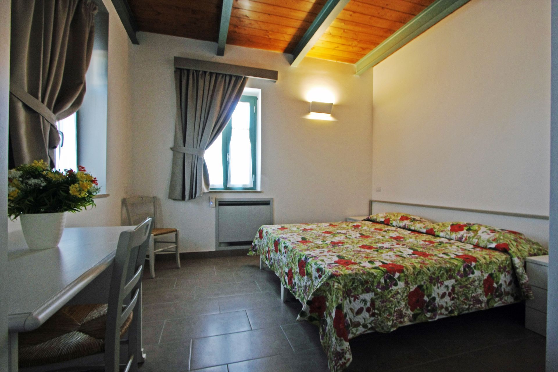 Una camera da letto con un copriletto a fiori, un soffitto in legno,