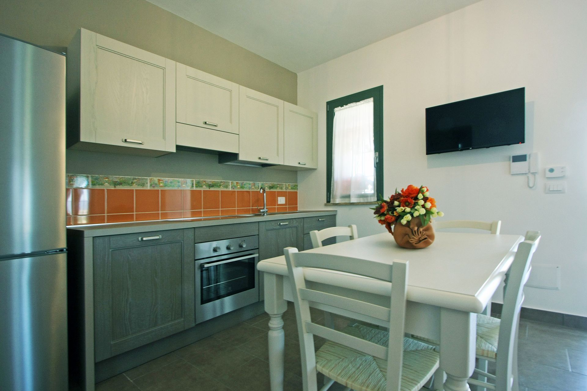 Una cucina luminosa con mobili chiari, pensili inferiori grigi